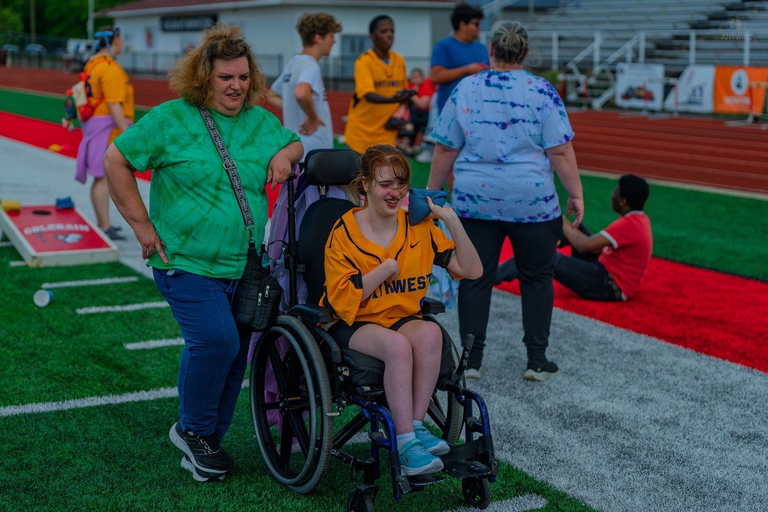 A volunteer assists a young woman in a wheelchair at a Special Olympics track and field event.