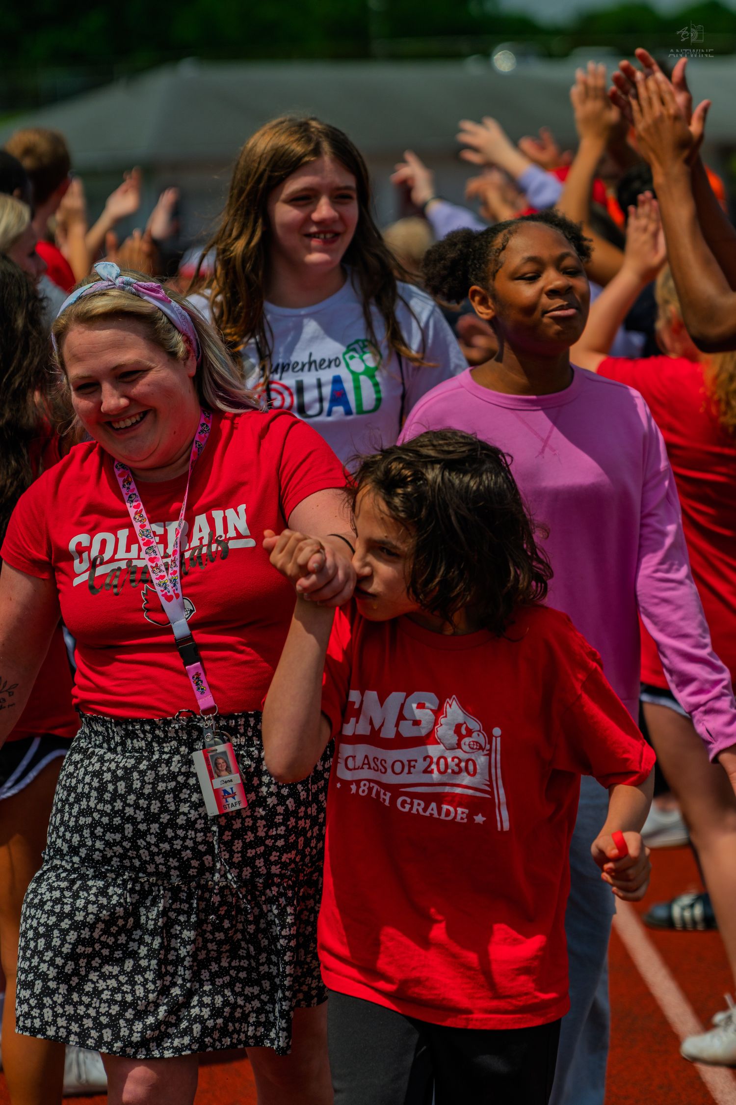 Students and teacher celebrate outdoors at a school event, wearing red EMS Class of 2030 shirts on a sunny day.