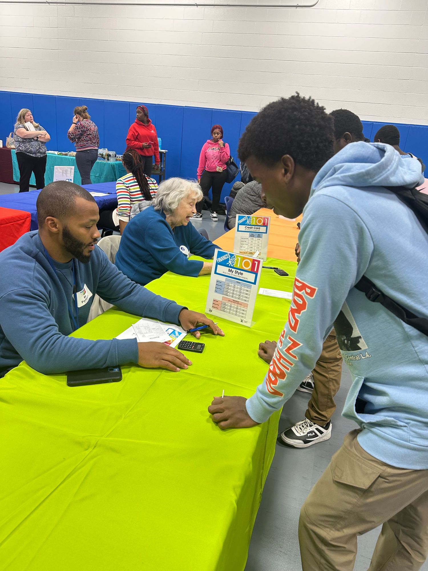 Students interact with representatives at a bright green table during an indoor school career fair.