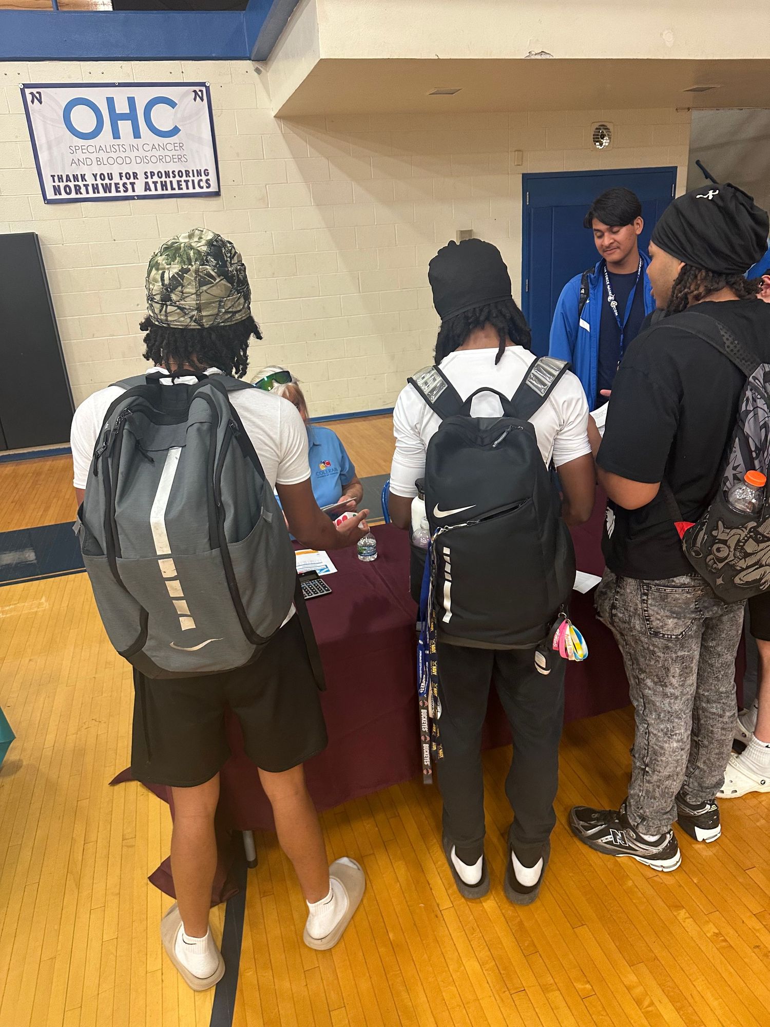 Students with backpacks gather at an OHC sponsored booth during a Northwest Athletics school fair event.