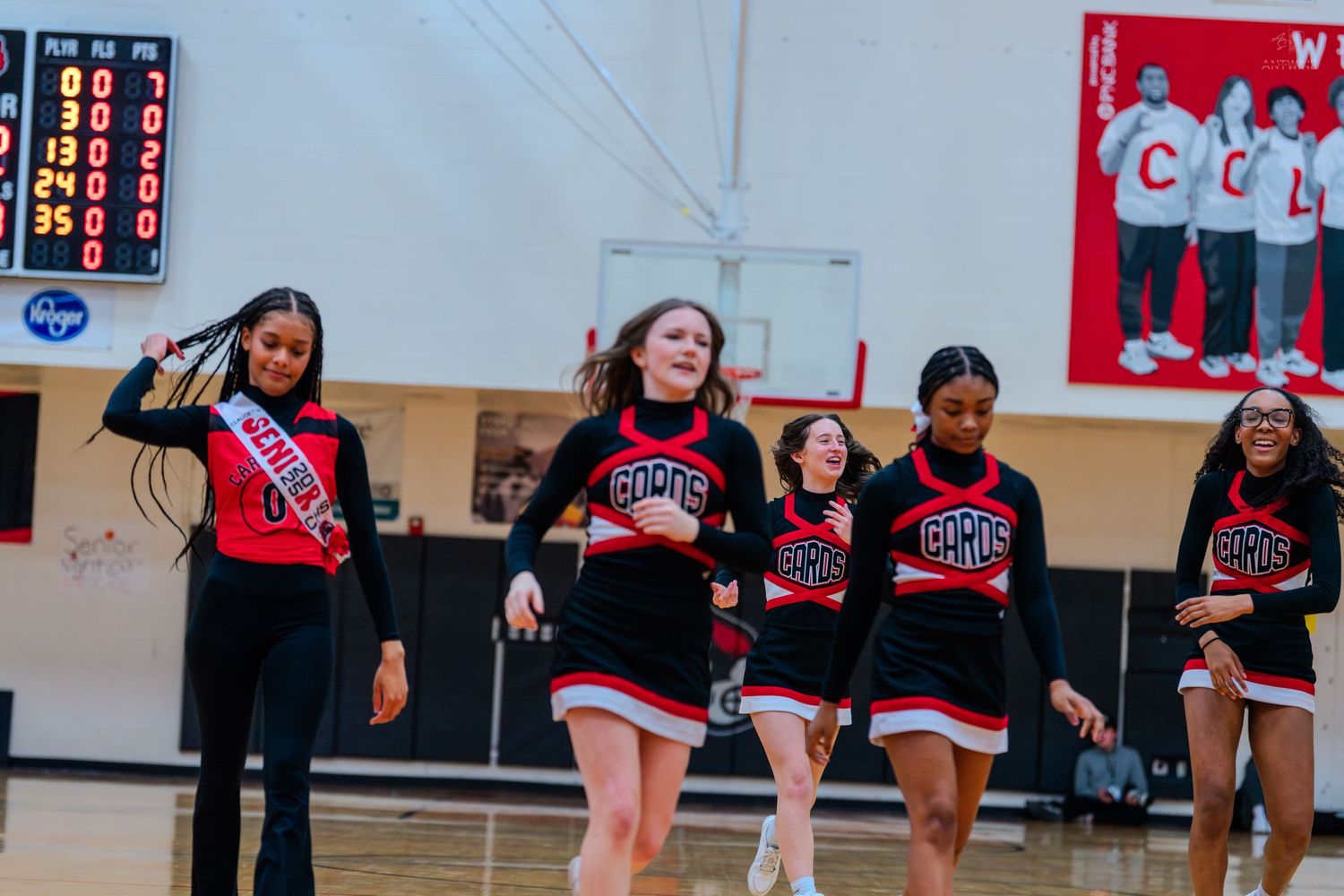 Coleman Middle School cheerleaders perform in red and black uniforms during a basketball game in the school gymnasium.