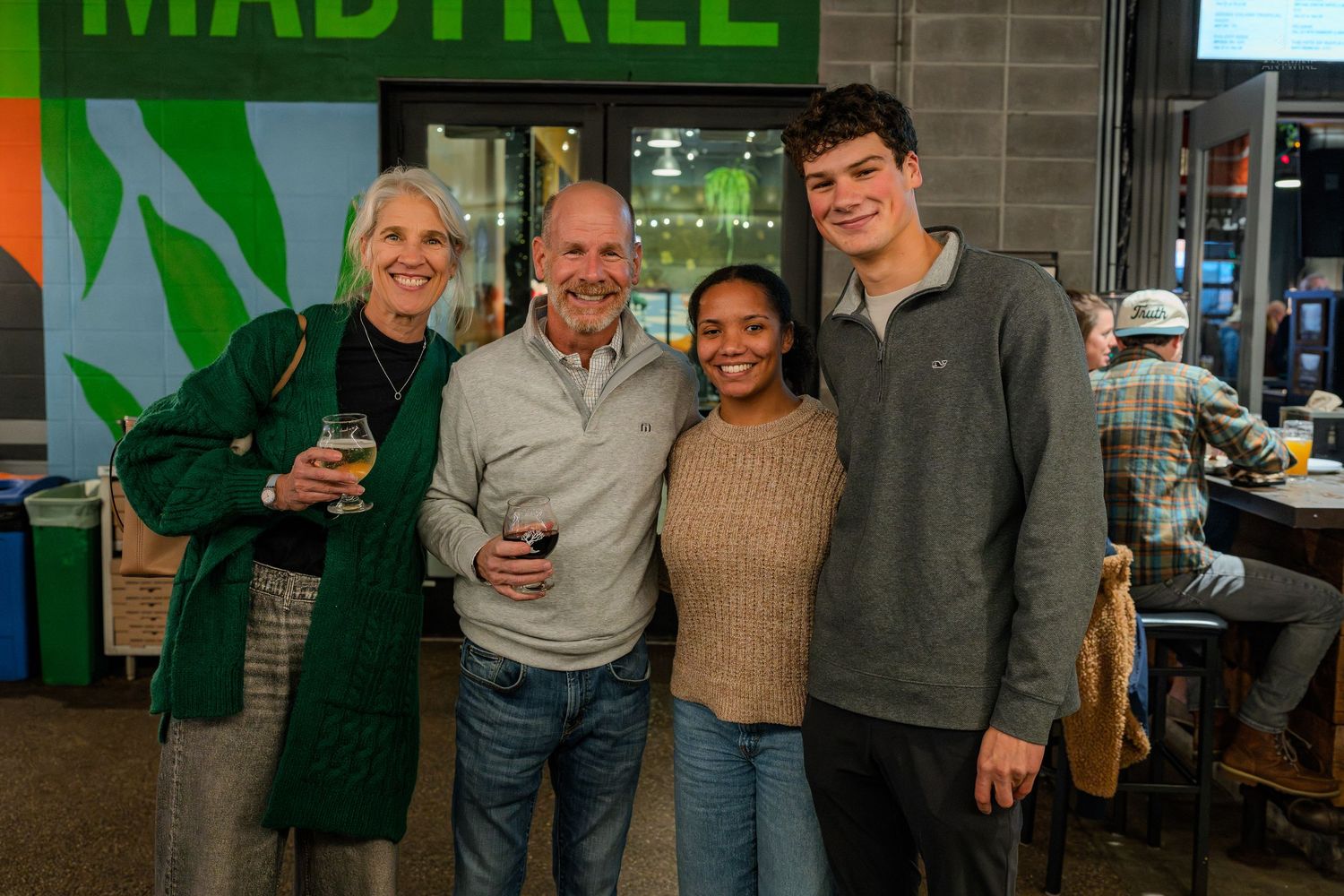 Four people pose together smiling inside Madtree Brewing taproom.