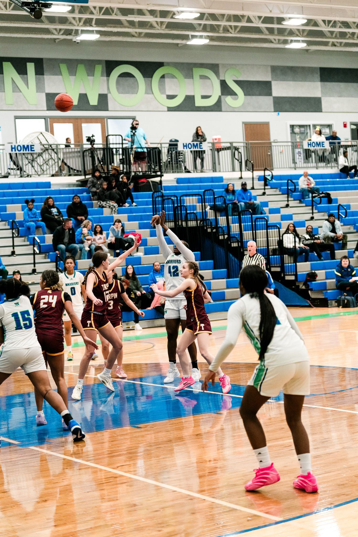Girls high school basketball players contest a shot near the key during a game at the Mason Woods gymnasium.