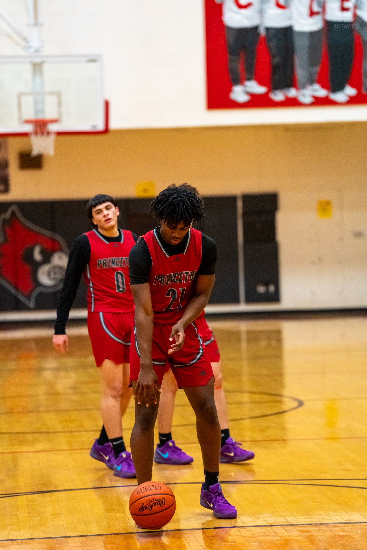 Princeton basketball players #20 and #0 line up for free throw attempt during high school game.