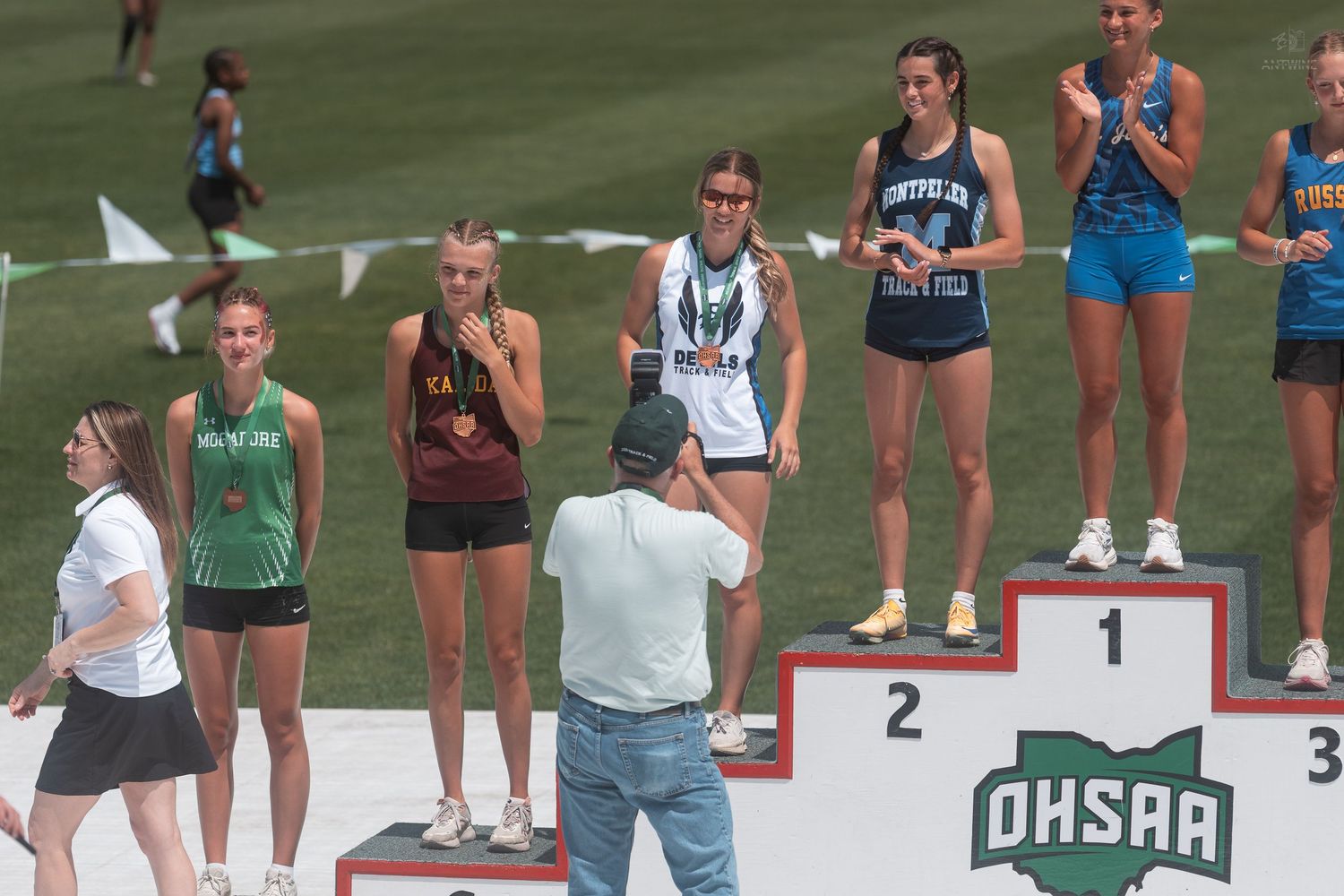 A girl is photographed on the OHSAA awards podium at a high school track and field state championship.