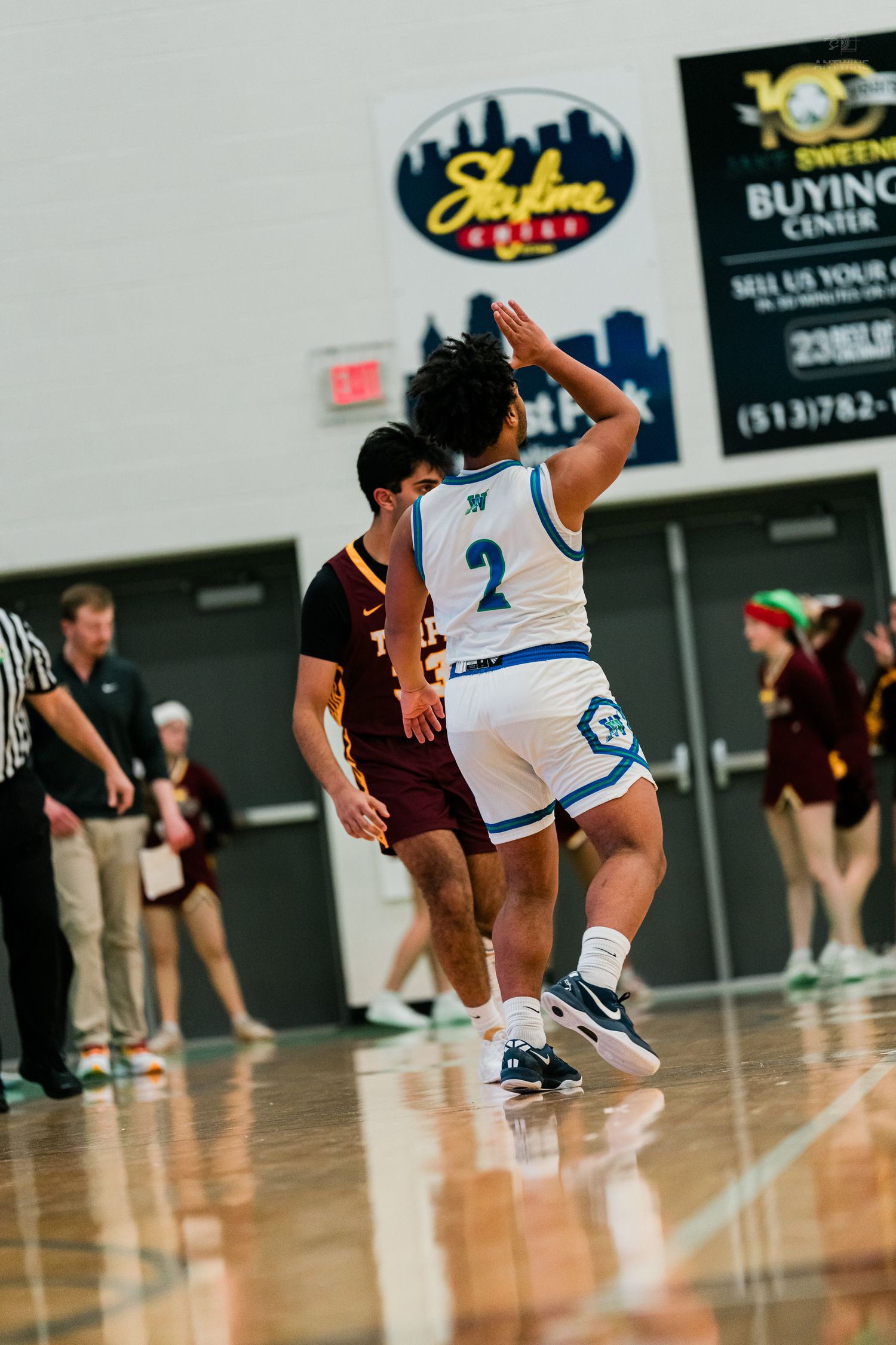 High school basketball player #2 in white Warriors uniform drives past a defender during a game.
