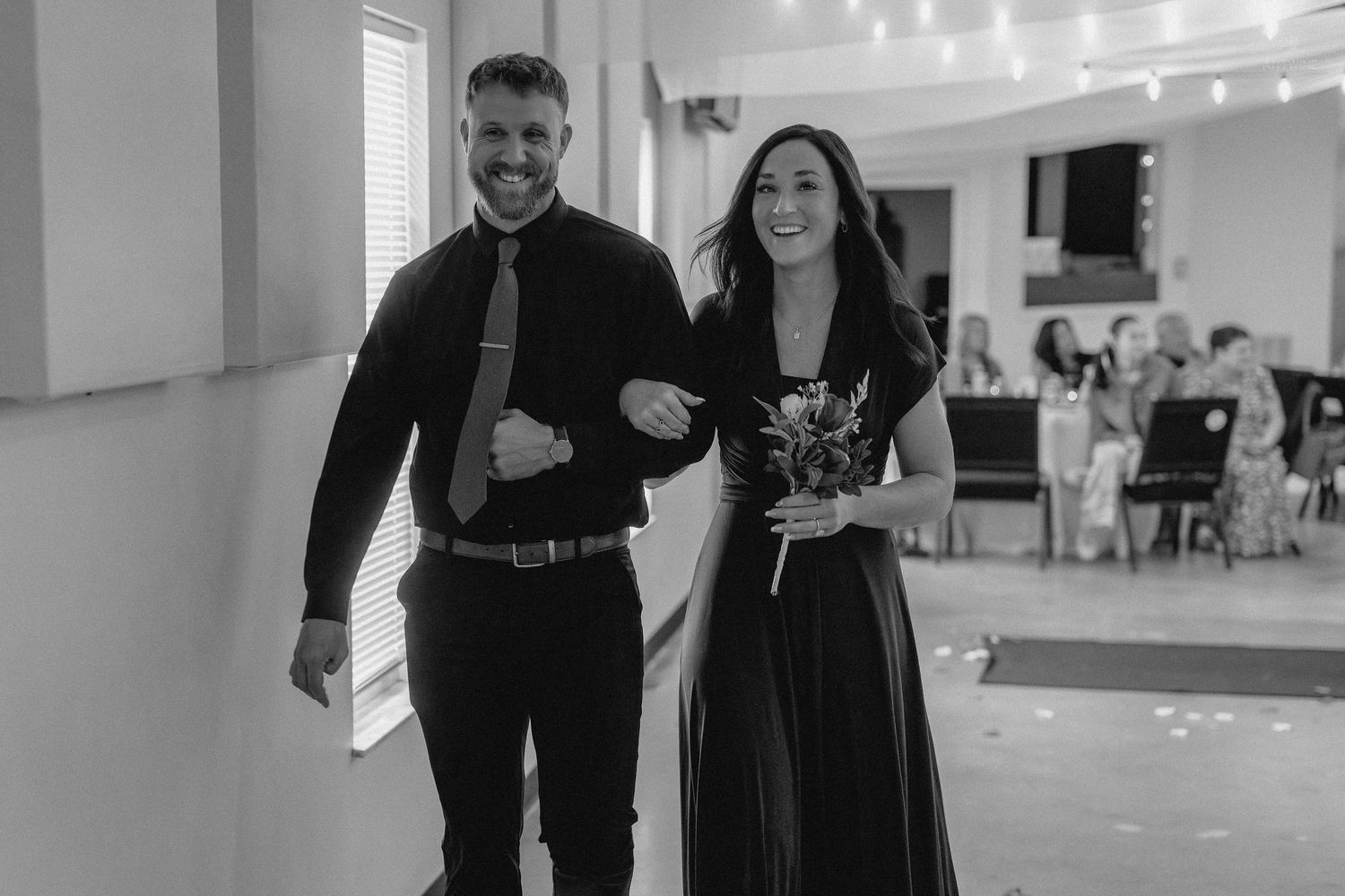 Bridesmaid and groomsman walk together smiling during wedding reception grand entrance.