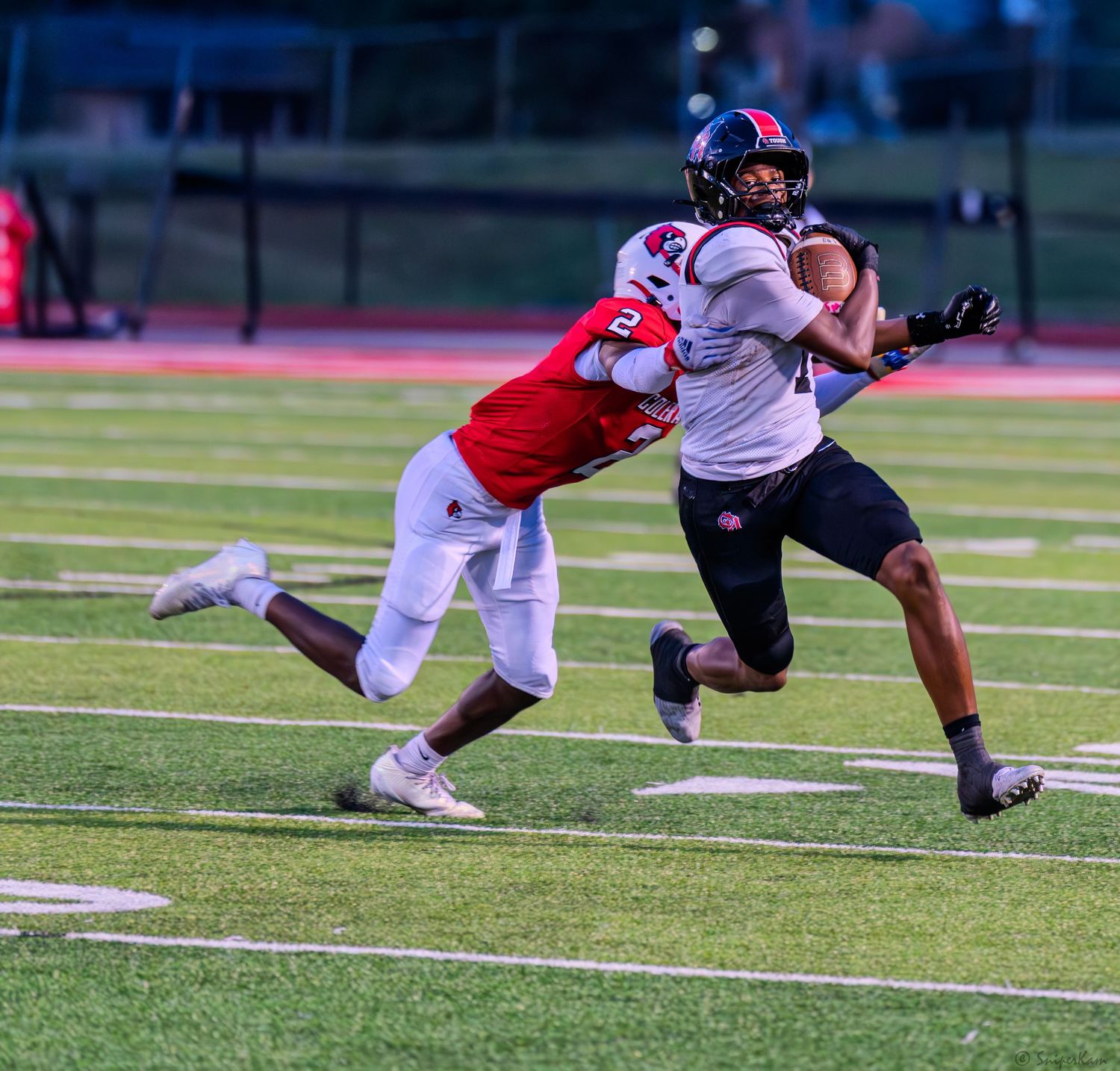 Colerain defender number 2 tackles opposing receiver during an intense high school football game at night.