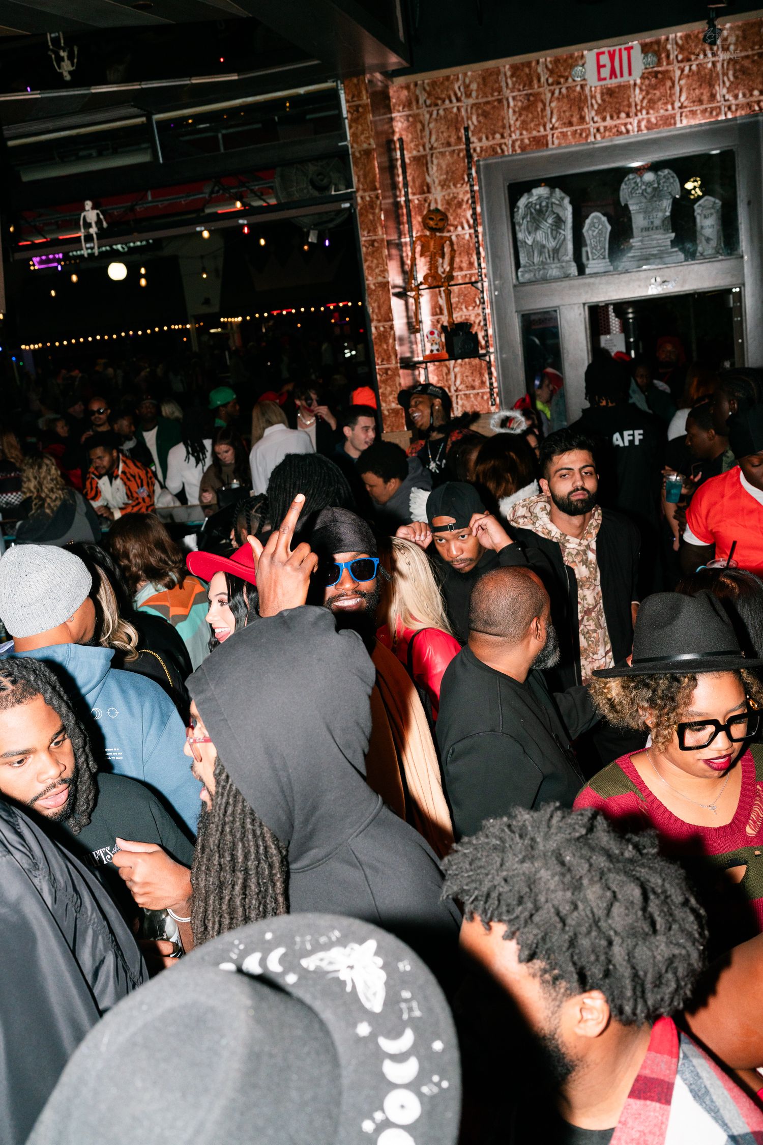 Large diverse crowd enjoying a Halloween party at a packed indoor venue.