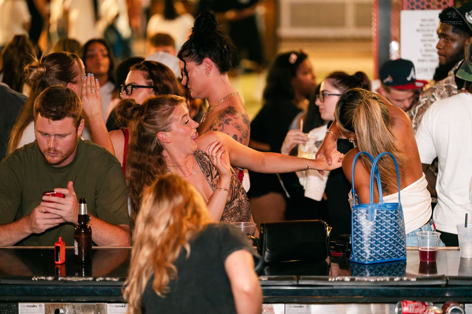 Friends laughing and socializing at an outdoor bar counter during a lively nightlife gathering.