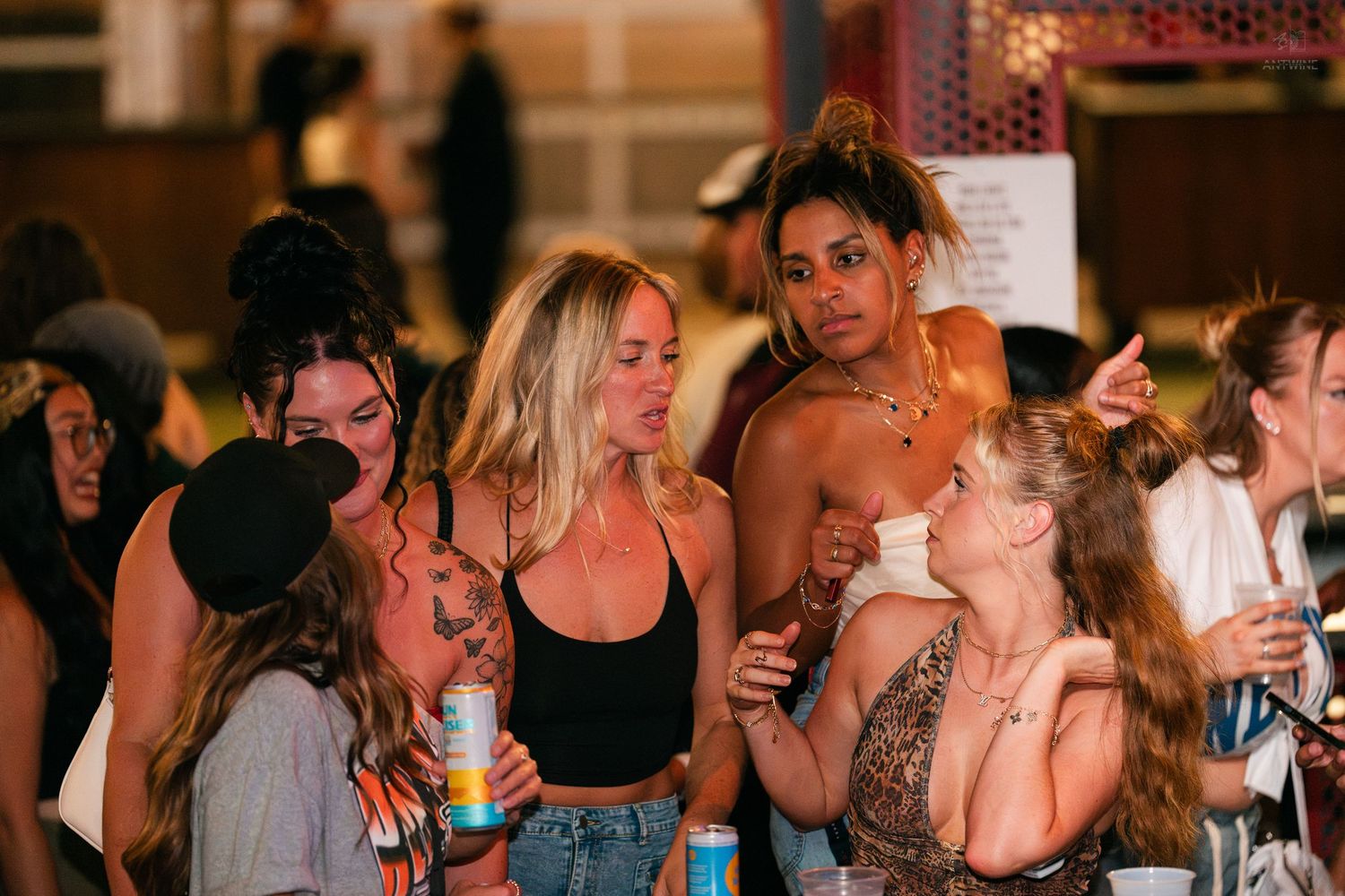 Group of young women socializing outdoors at a nighttime event.
