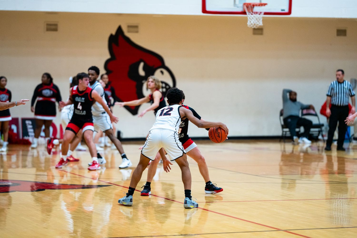 High school girls basketball game with players in red and white uniforms defending near the basket on an indoor court.