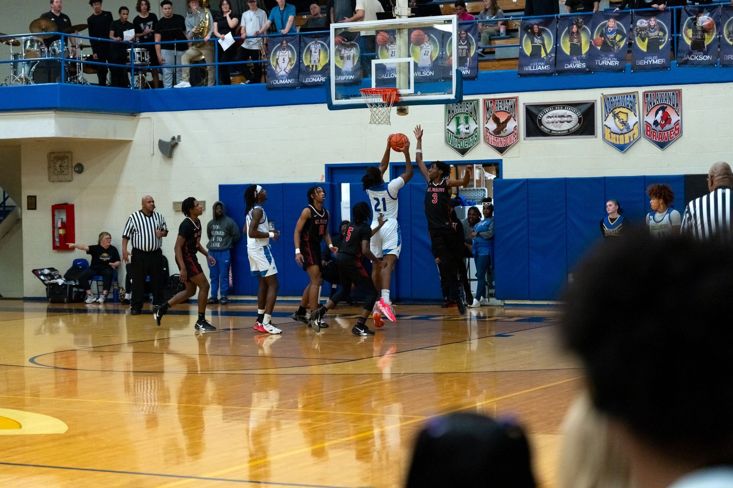 High school basketball player attempts a shot near the basket during a competitive indoor game.