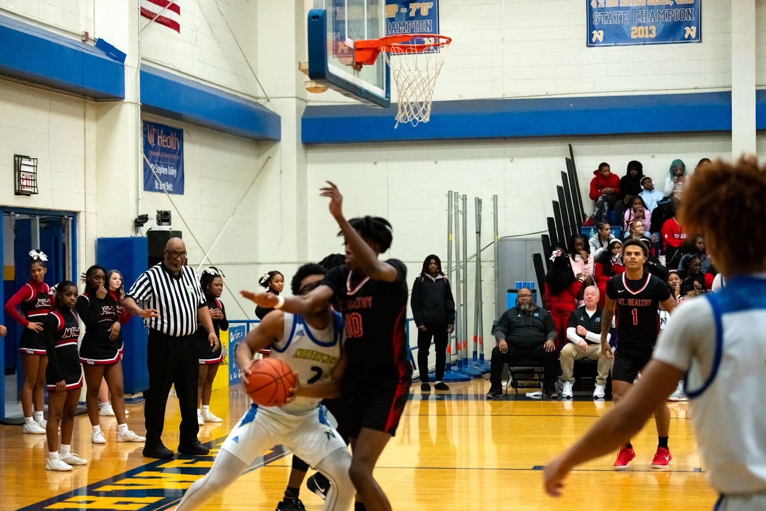 Knights basketball player drives to basket against defenders during intense high school game.