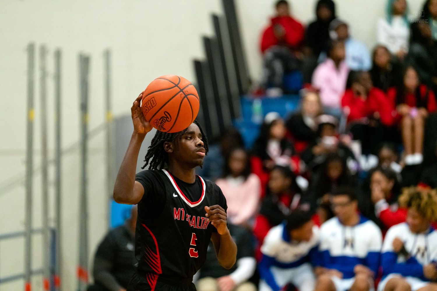 A basketball player in a red uniform prepares to shoot during a high school basketball game.