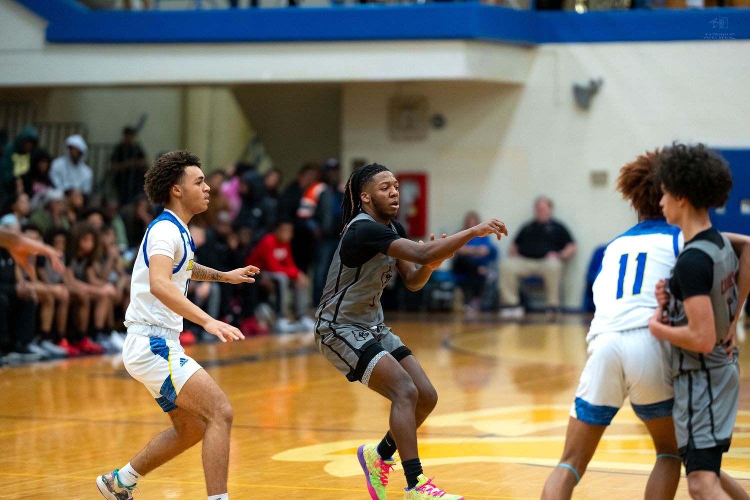 Basketball player in dark uniform drives aggressively toward the basket during a high school gymnasium game.