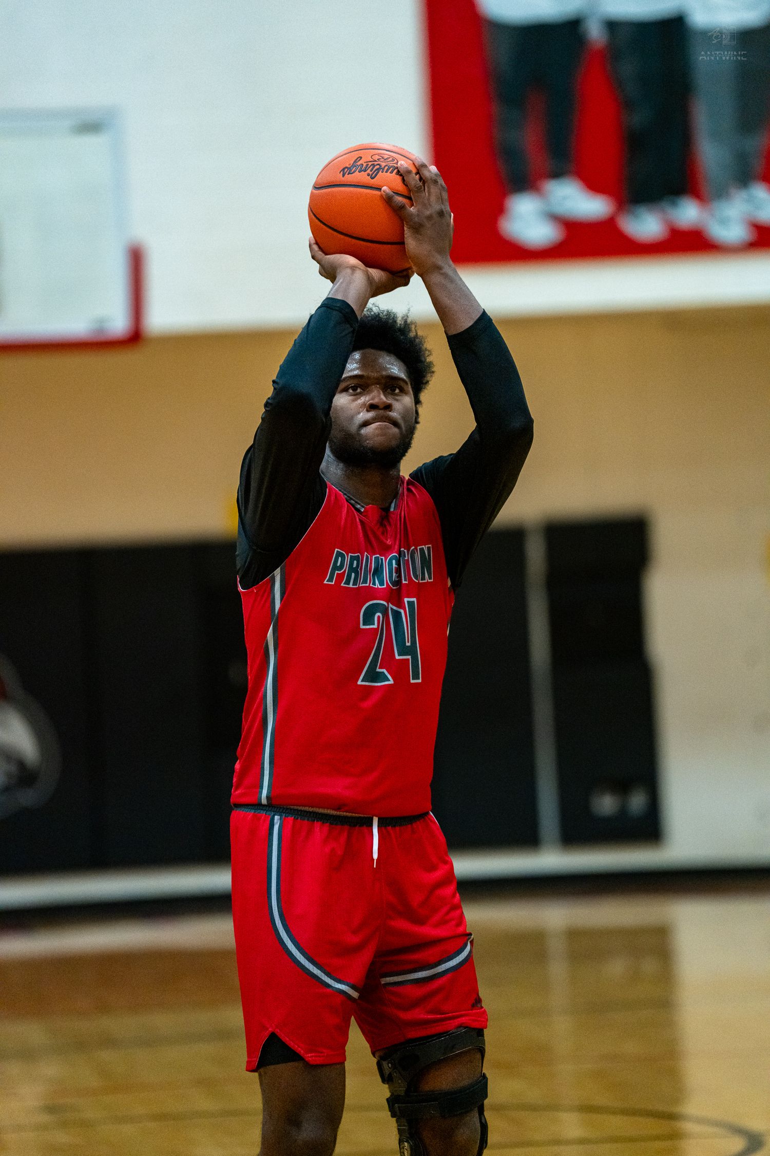 Princeton #24 shoots a free throw during a high school basketball game in a red uniform.