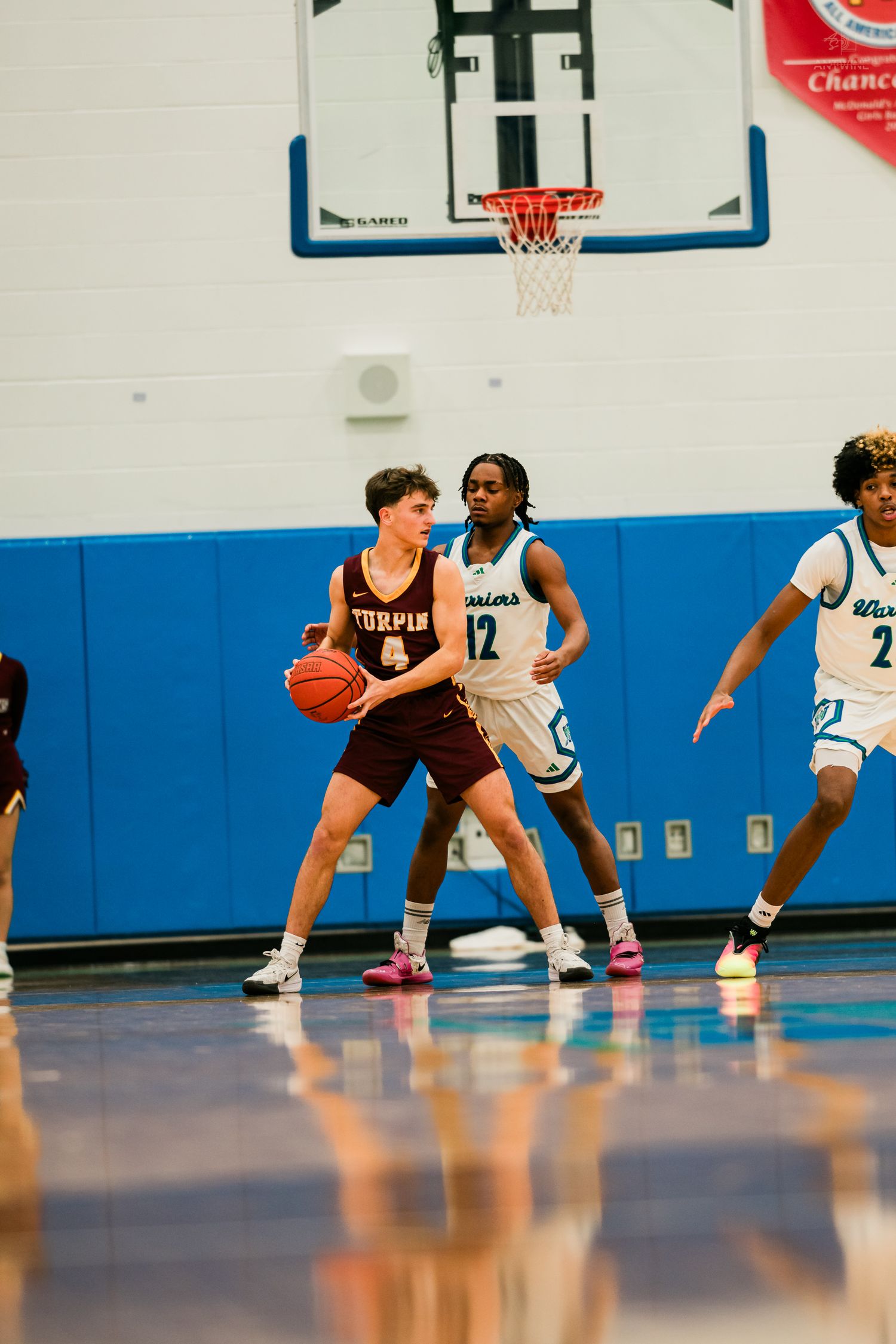 Turpin player number 4 protects the ball while Warriors defenders number 12 and 2 apply pressure.