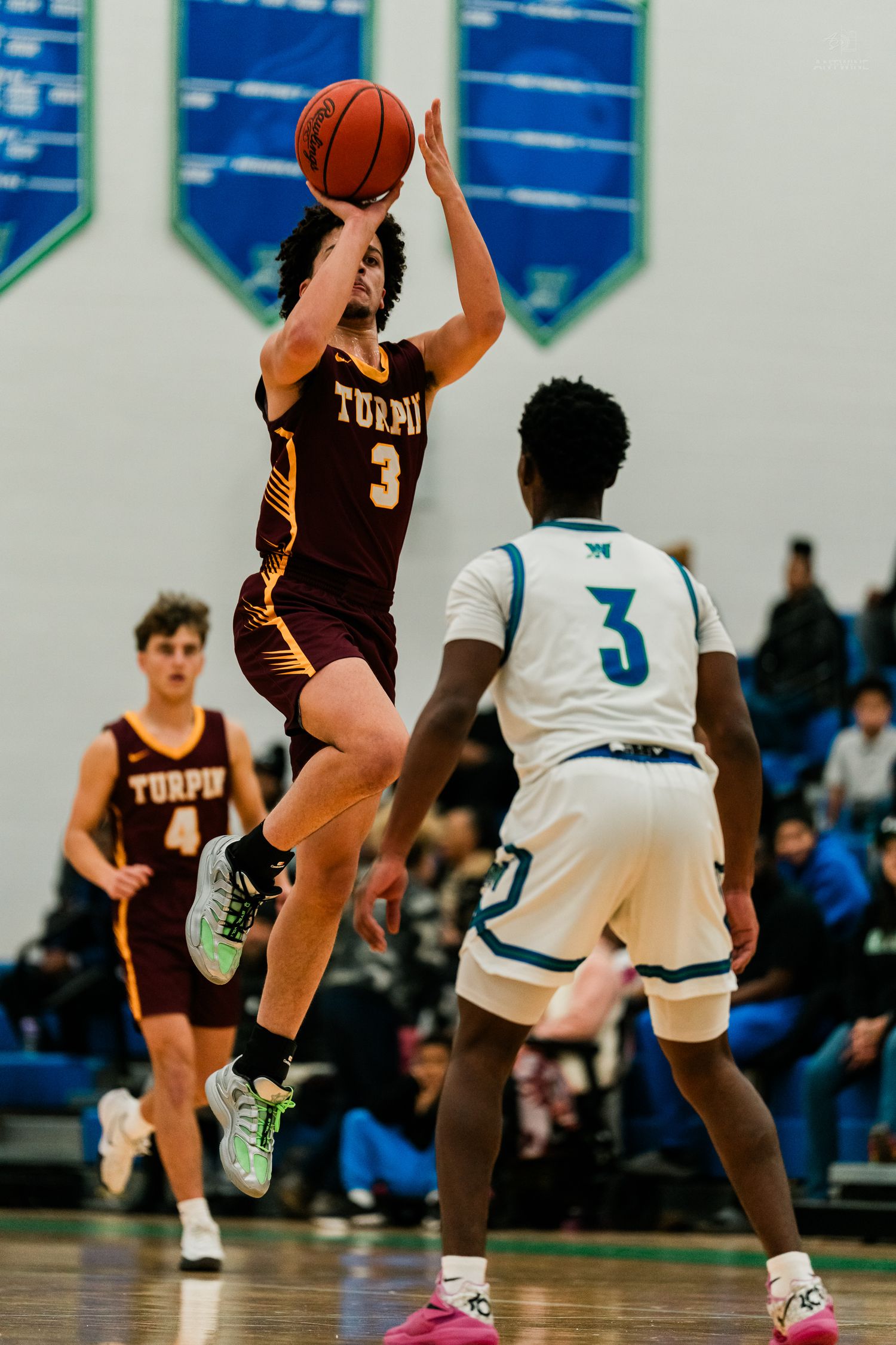 Turpin number 3 player leaps for a jump shot over a Warriors number 3 defender in high school game.