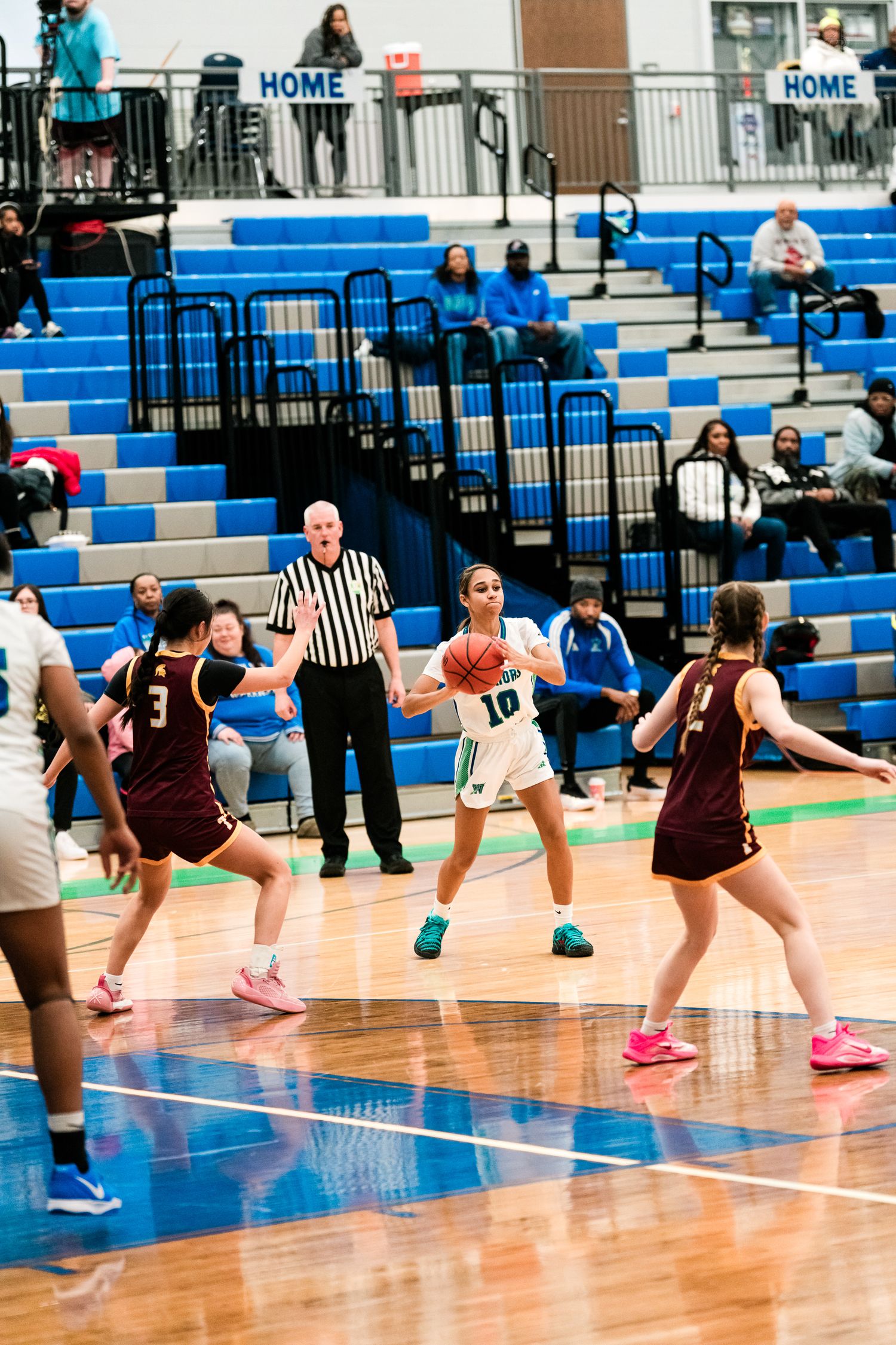 Player #10 in white uniform looks to pass while defended by maroon-uniformed players during a girls high school basketball game.