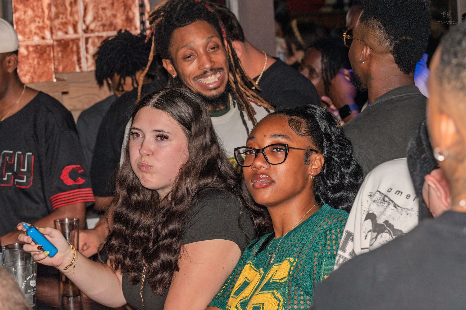 Group of friends socializing and posing together at a lively indoor bar or nightclub event.
