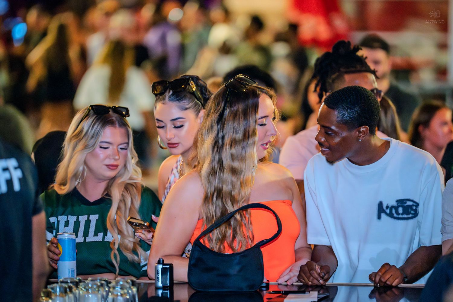 Group of young adults gathered around a bar counter at night.