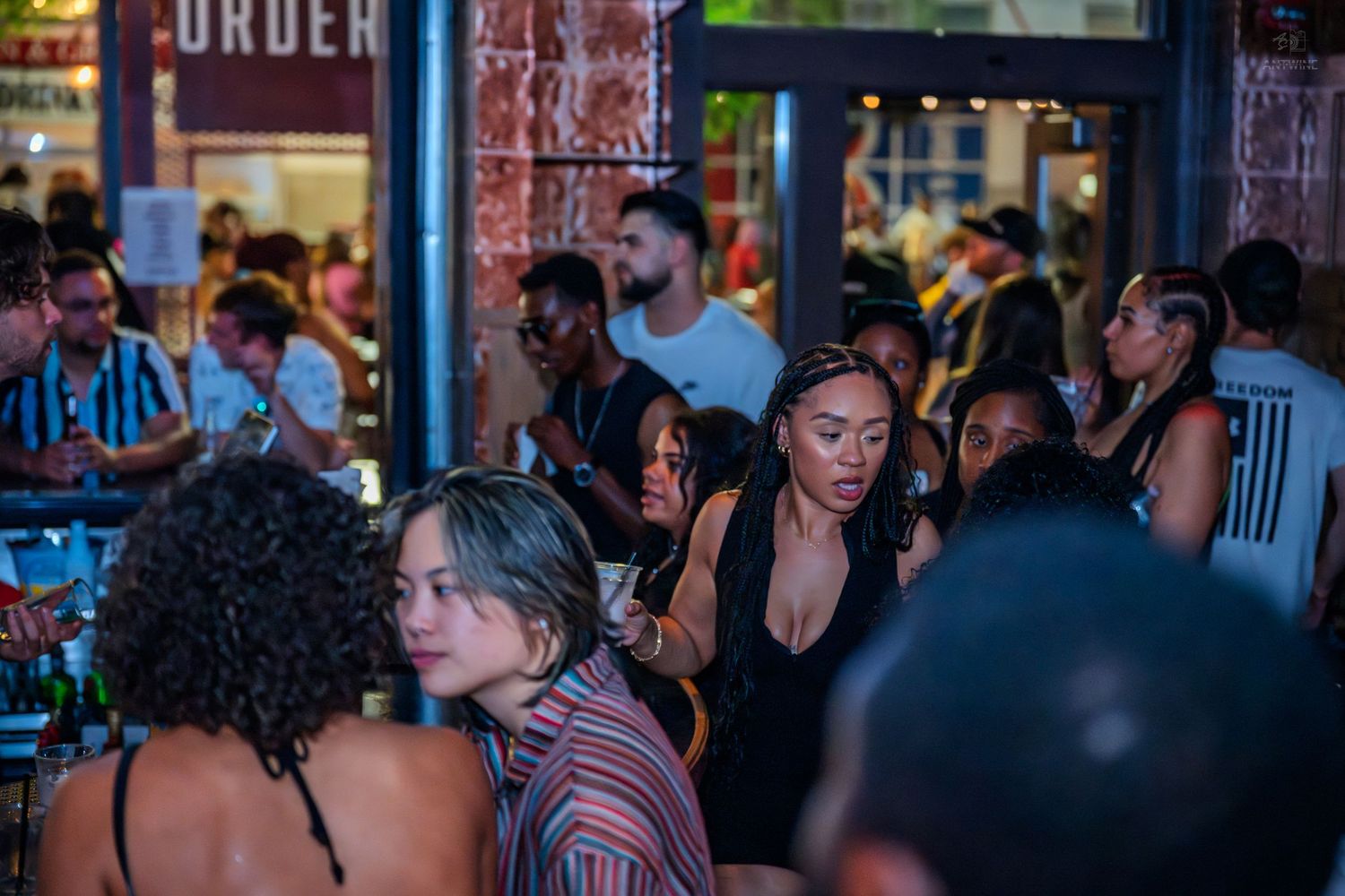 Diverse crowd of people mingling at a busy outdoor bar at night.