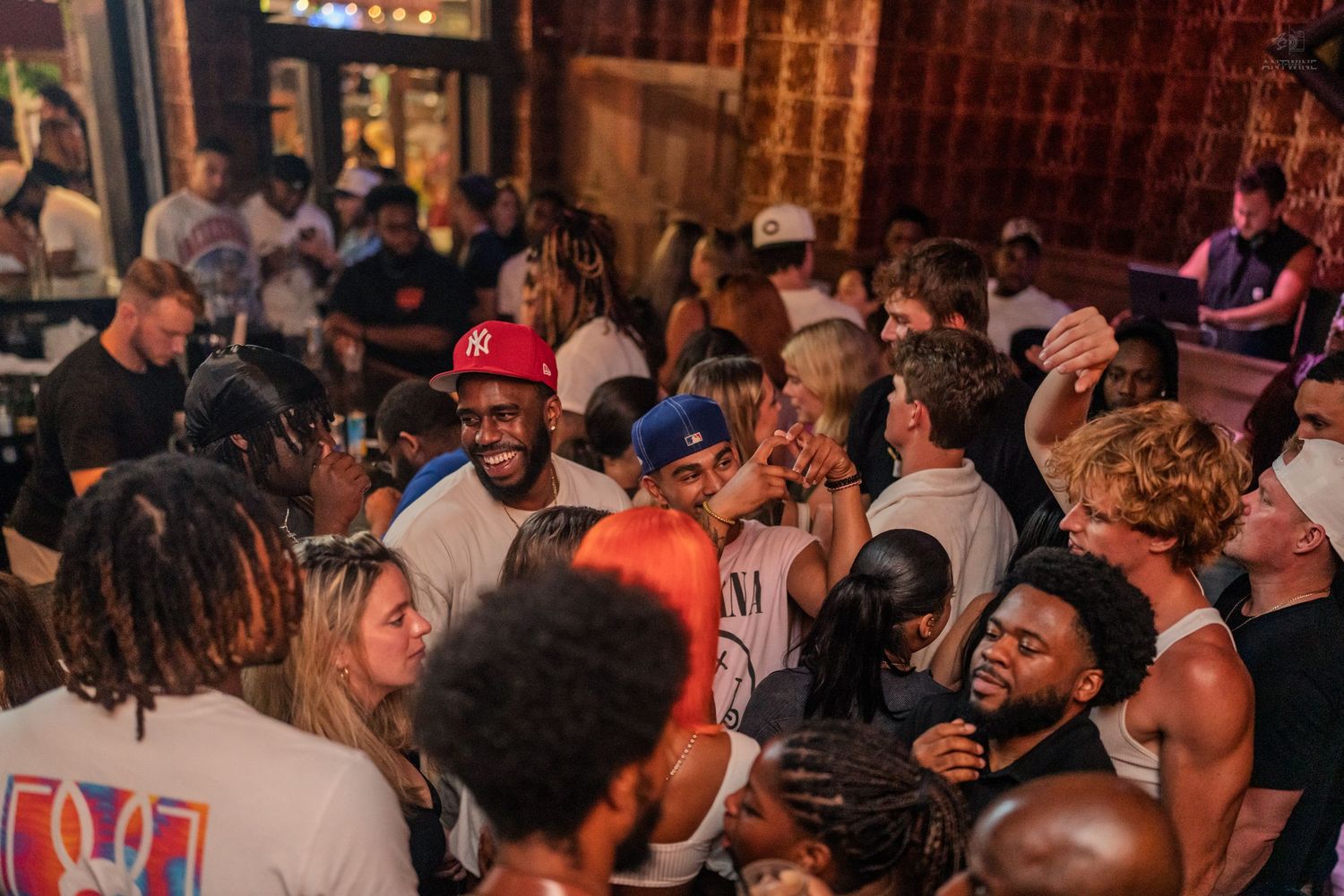 Large diverse group of young people laughing and celebrating together at a lively indoor party event.