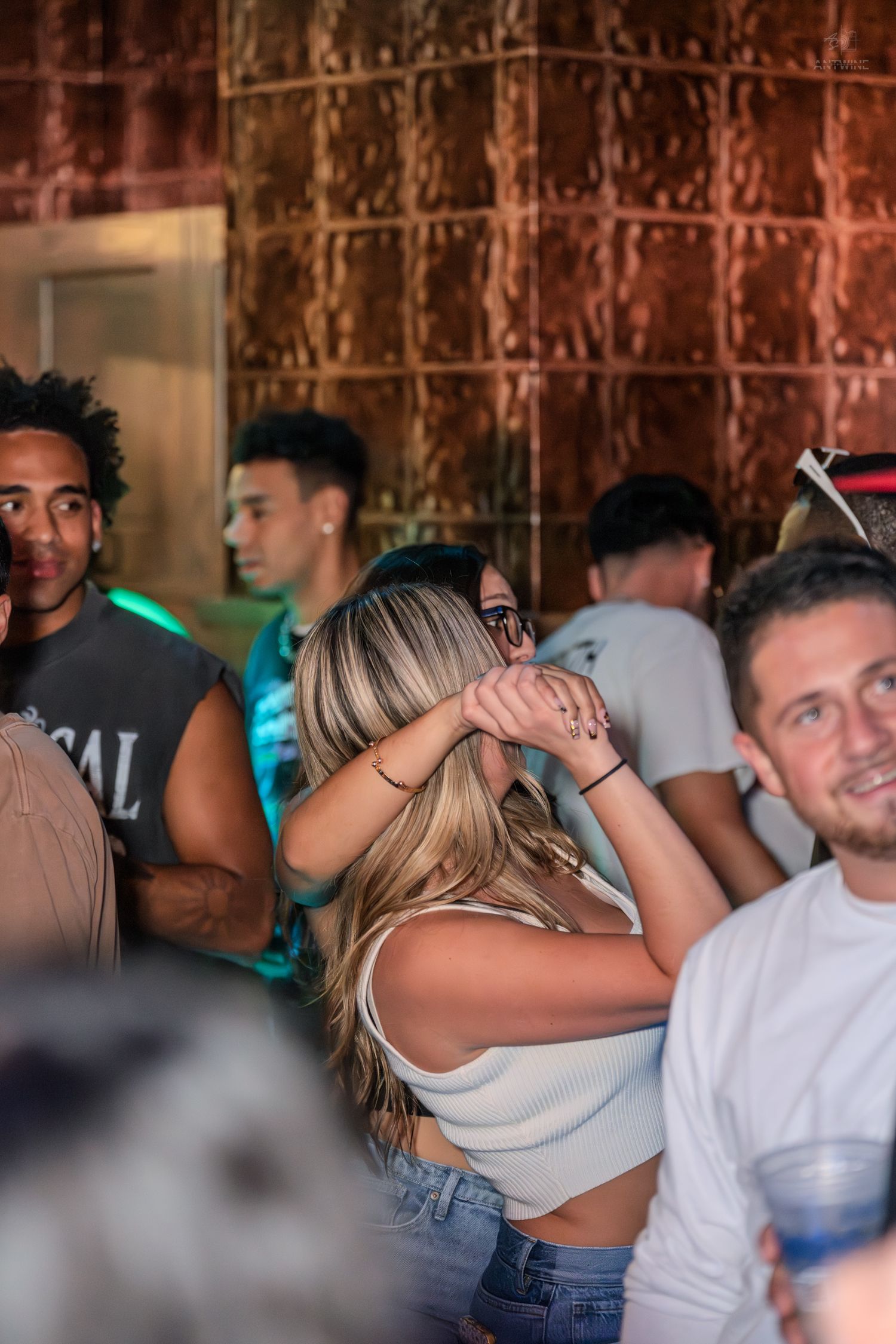 Group of young people socializing and dancing at a lively nightclub event.