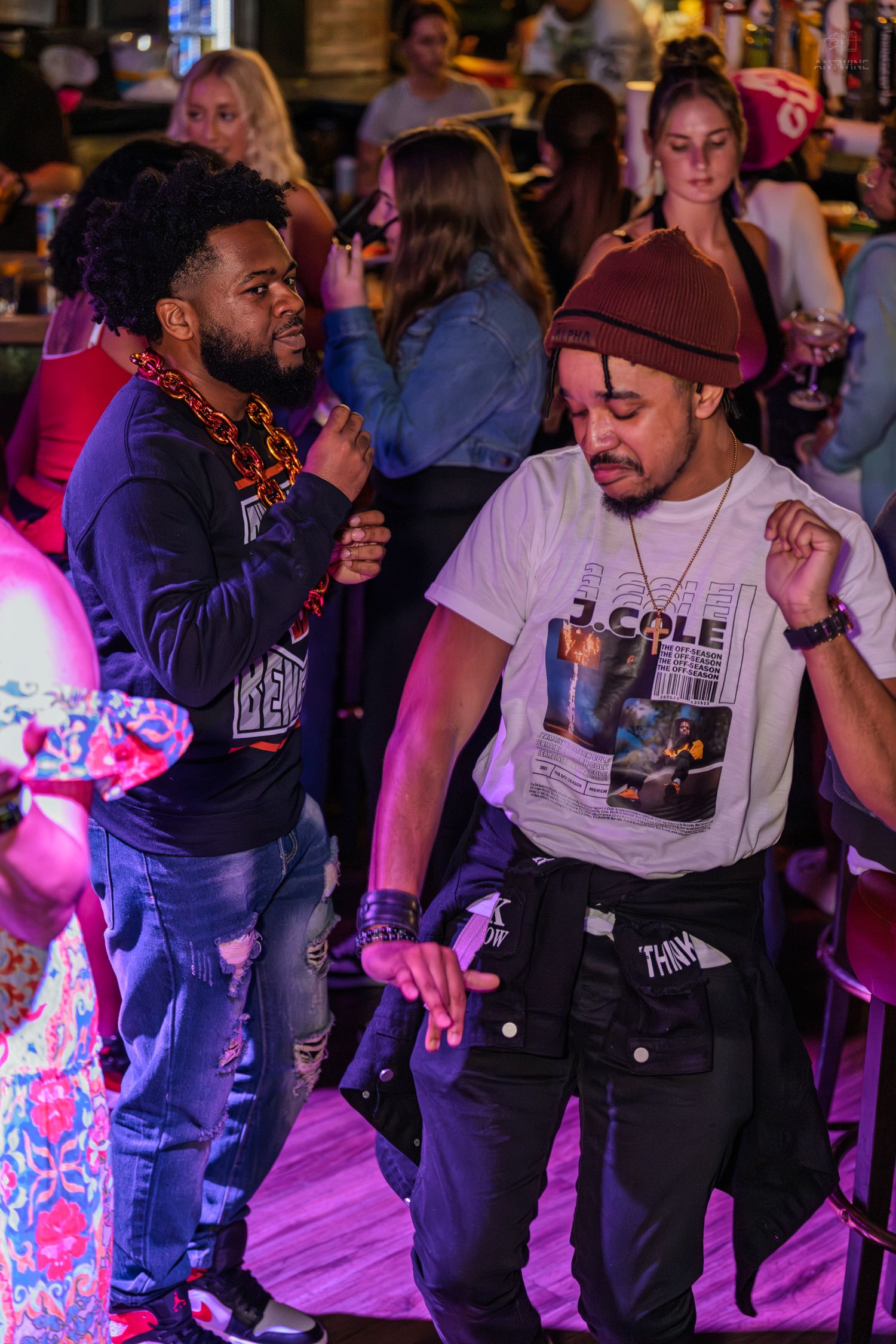 Two men dancing energetically at a lively bar party event.