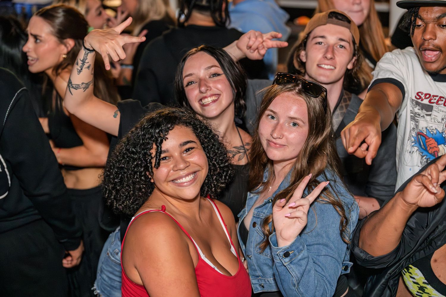 Cheerful group of friends posing and smiling together at an outdoor evening concert.