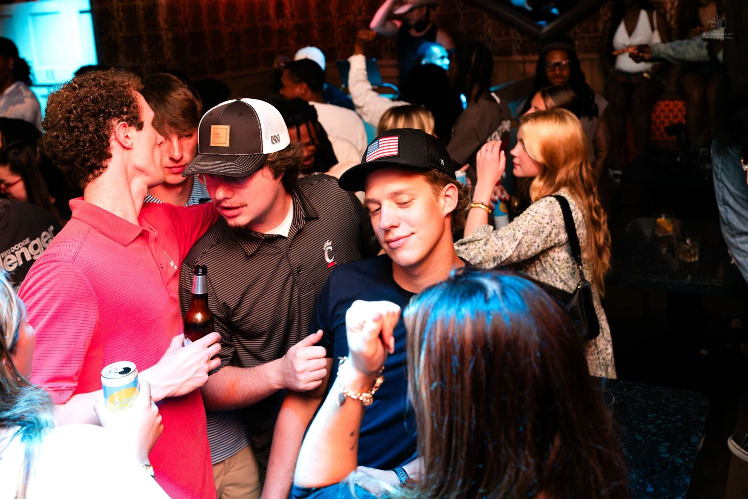 Group of friends in caps laughing together at a nightclub event.