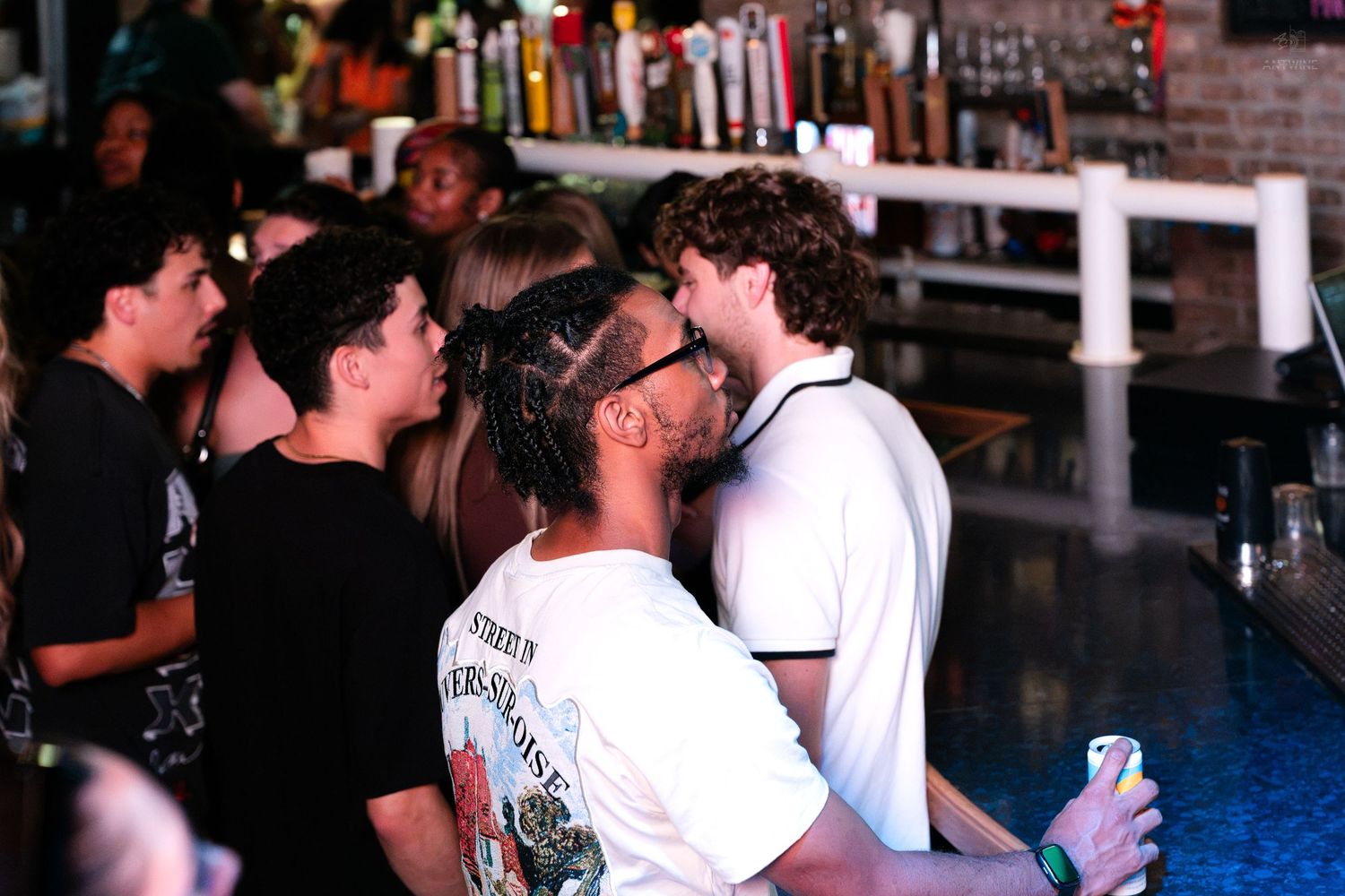 Group of young people socializing and chatting near a bar at a nightclub event.