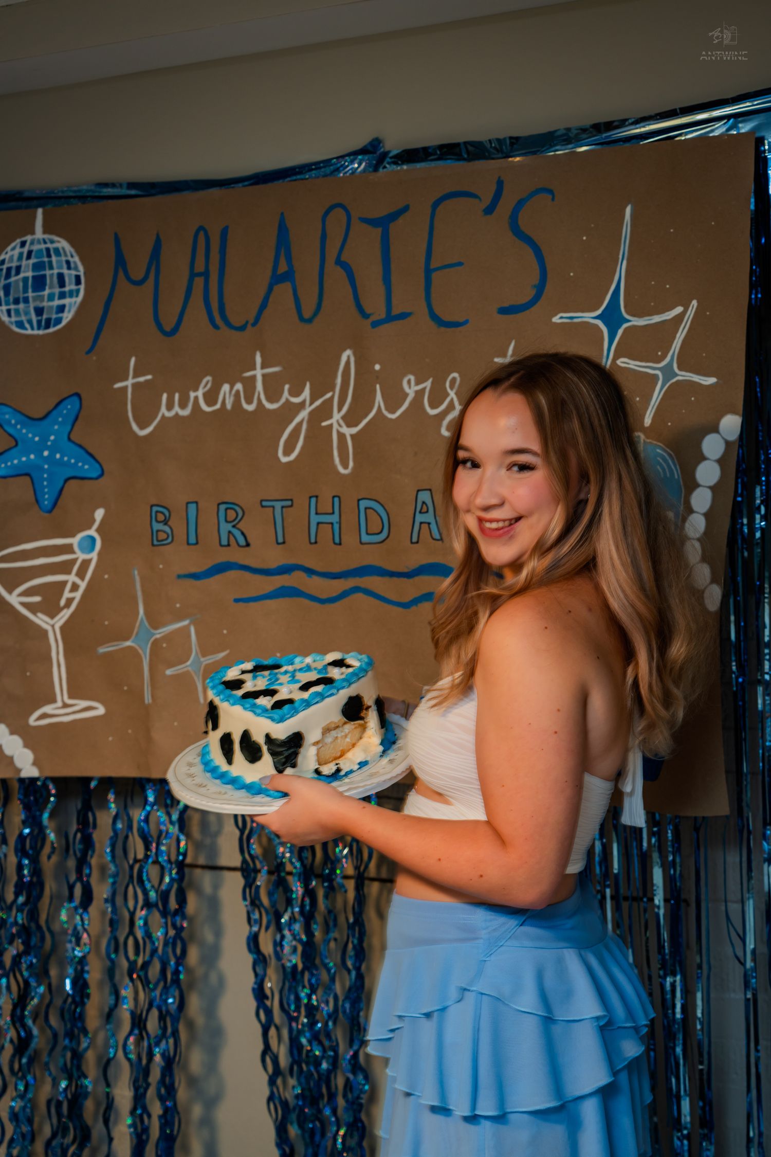 Happy young woman poses with heart-shaped cake at Malarie's twenty-first birthday celebration.