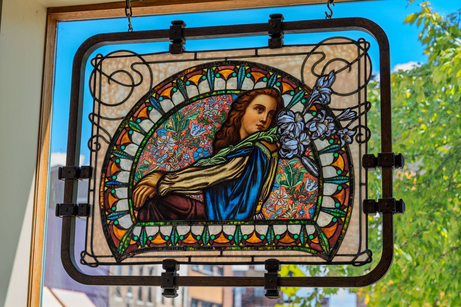 Ornate stained glass window panel depicting a woman with flowers in an Art Nouveau style frame.