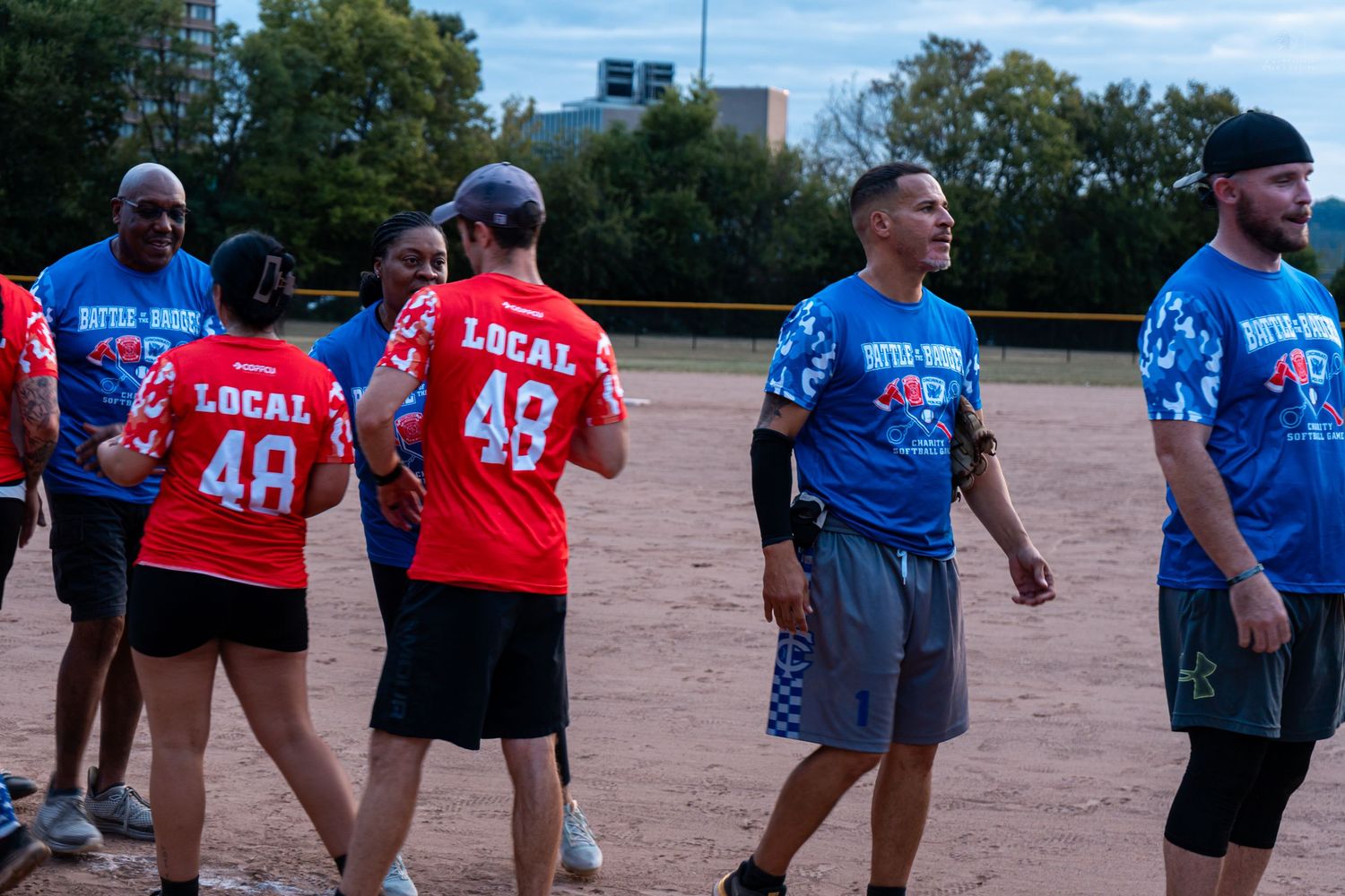 Local 48 softball team players in red and blue jerseys on baseball field.