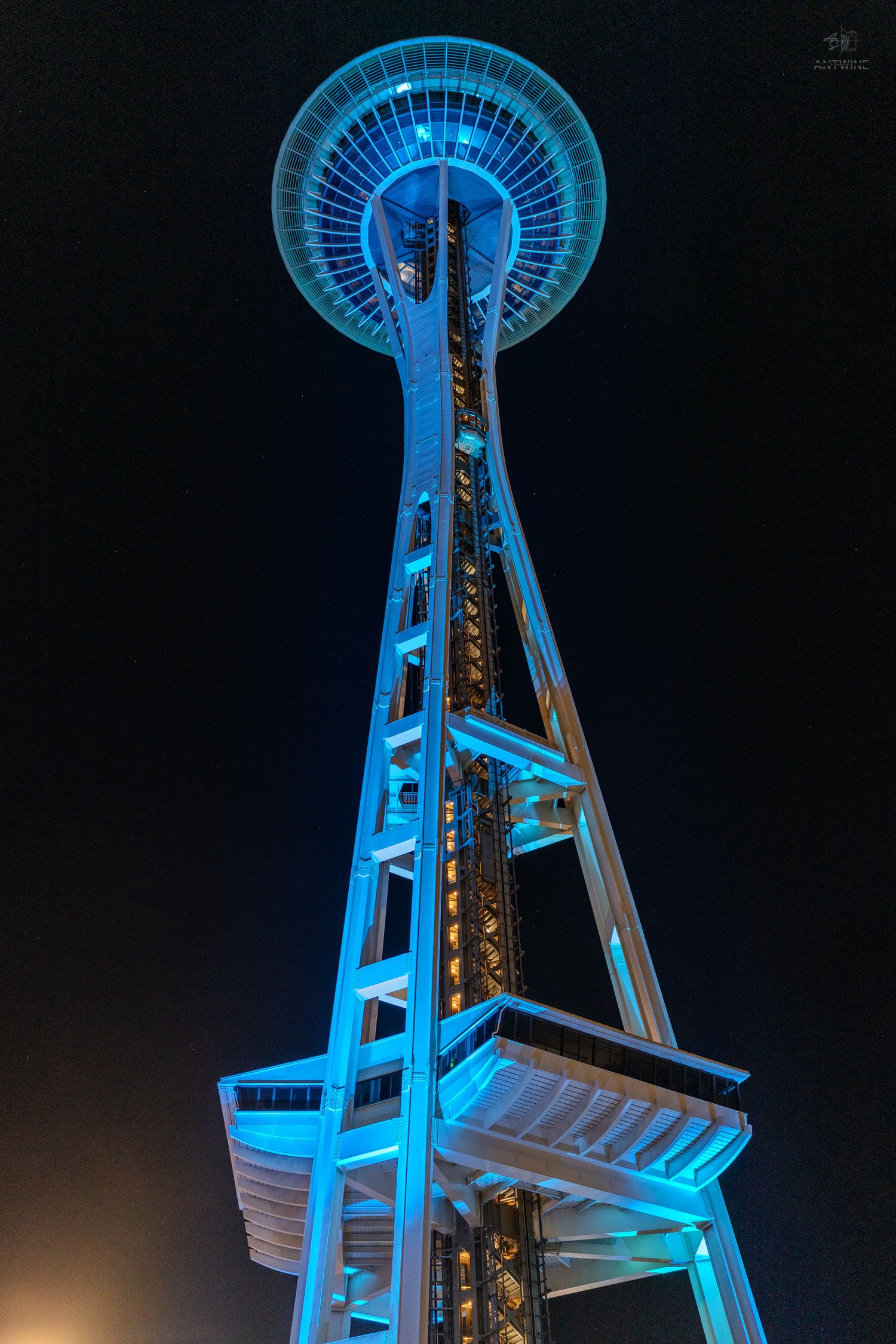 Seattle Space Needle illuminated in blue light photographed from below against dark night sky.