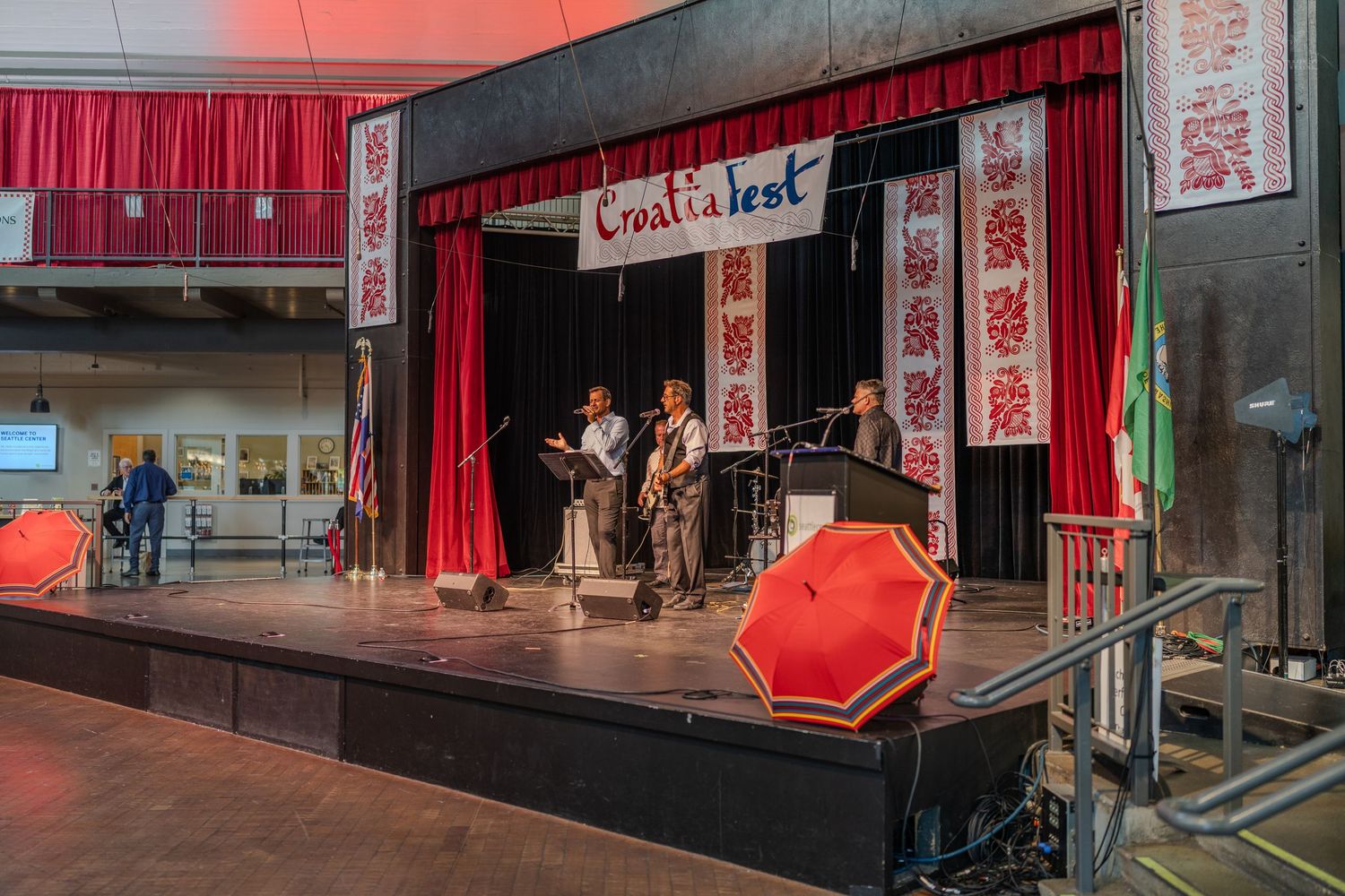 Small band performs on stage at CroatiaFest event with red curtains and traditional Croatian decorative banners.