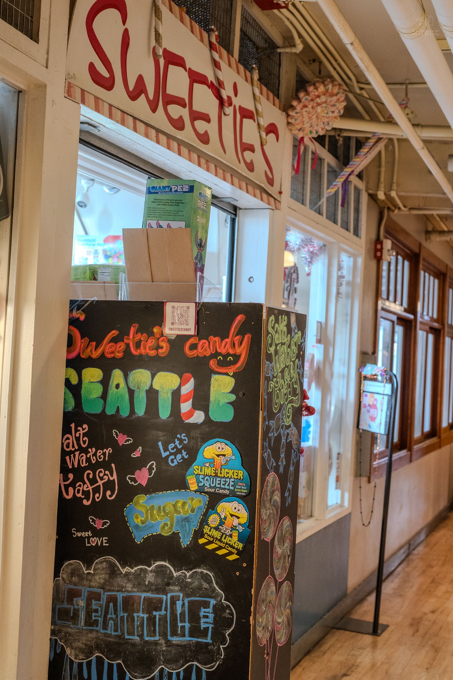 Sweetie's Candy shop entrance in Seattle with colorful chalkboard sign displaying Seattle branding and candy advertisements.