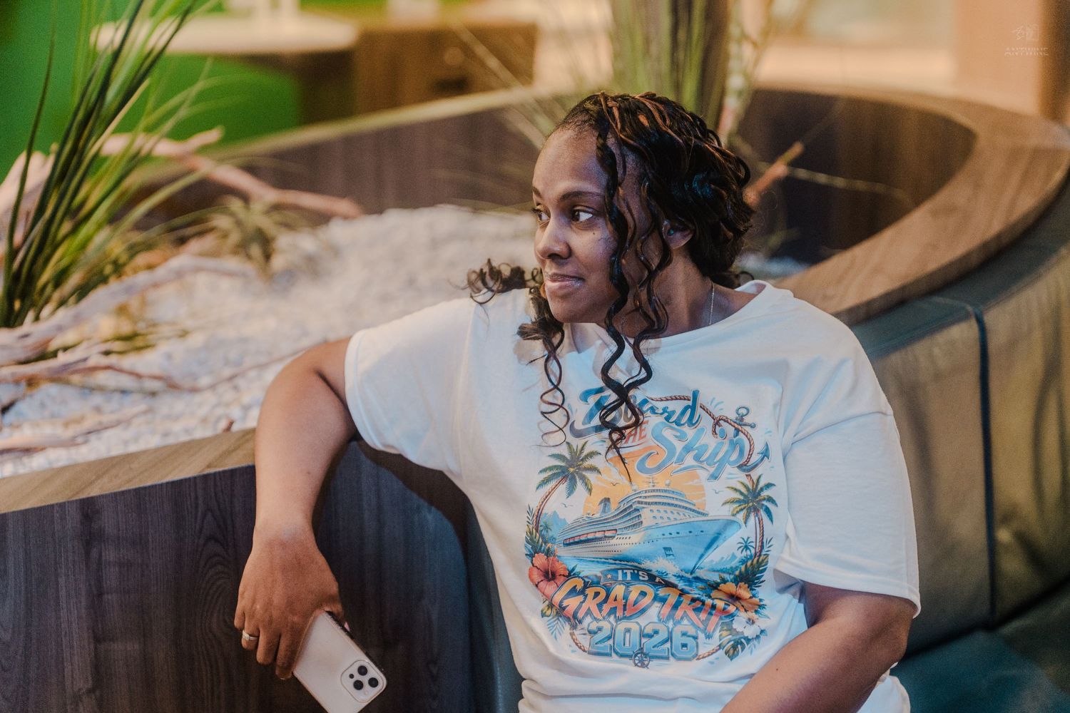 Young person in a white tropical cruise graphic t-shirt relaxing in a modern lounge area.