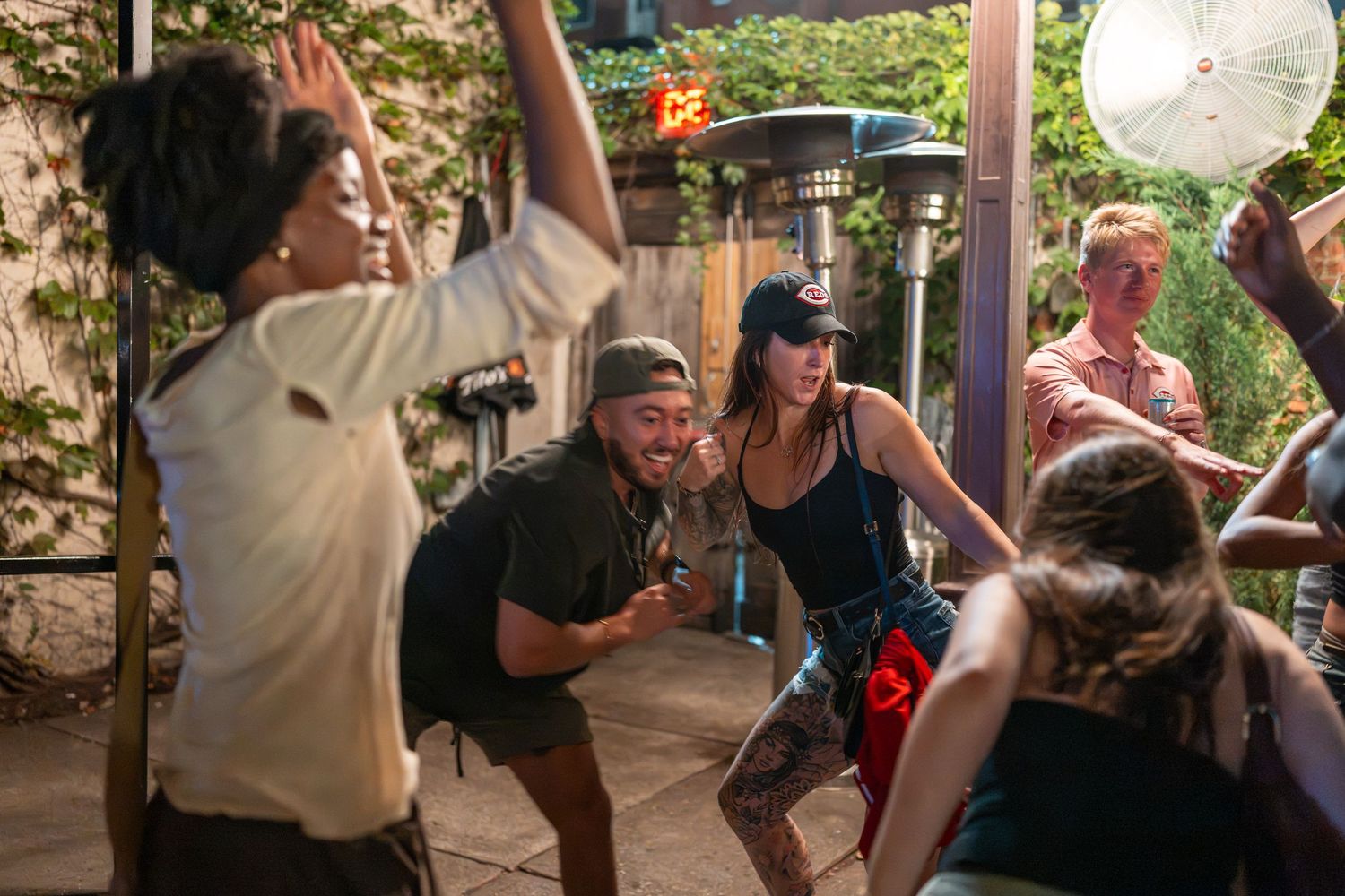 Group of friends dancing and celebrating outdoors at a patio party during a lively summer gathering.