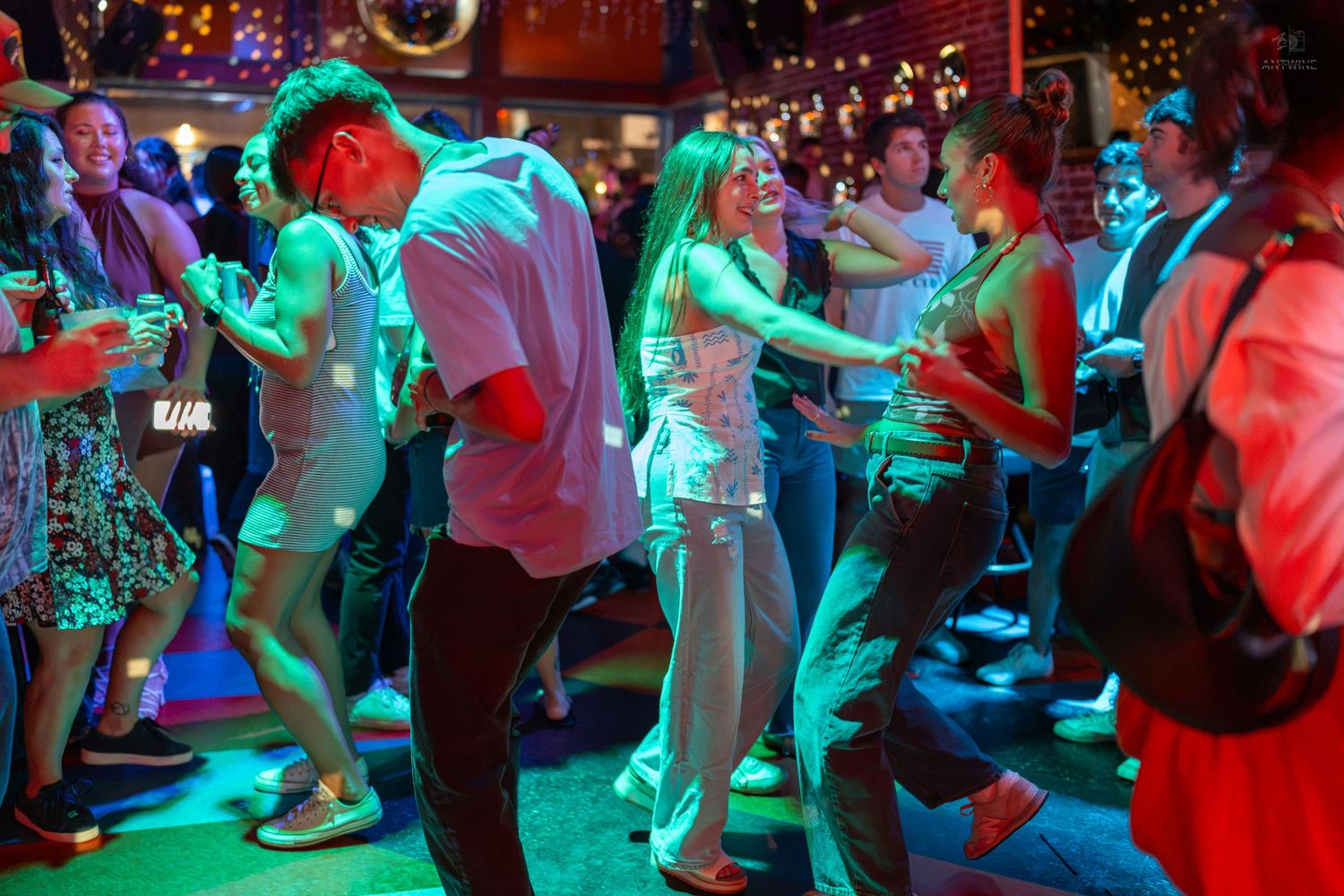 Energetic crowd dancing at a vibrant nightclub with colorful neon lights and lively atmosphere.