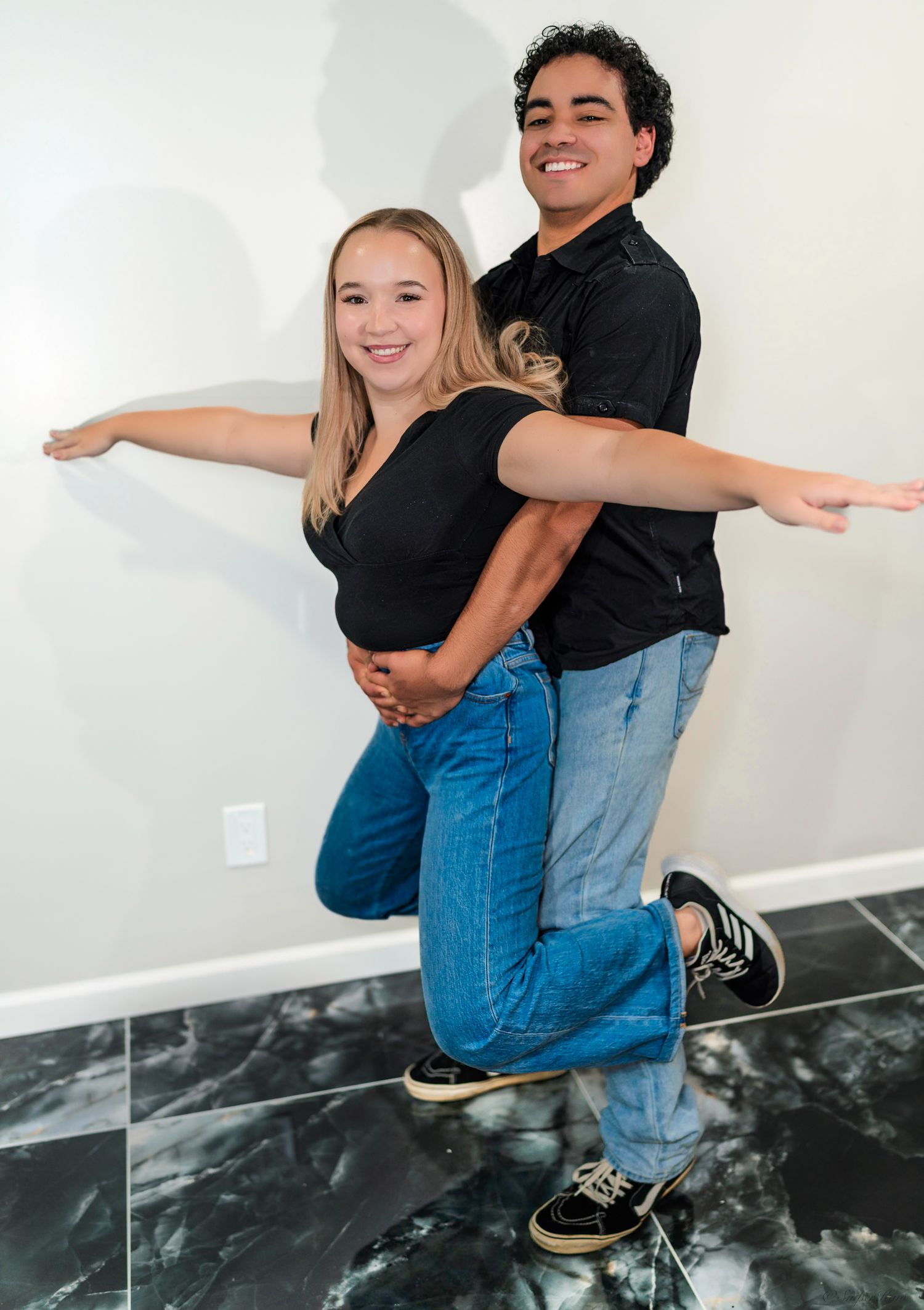 Two smiling young dancers posing together with arms outstretched in a fun studio photo.
