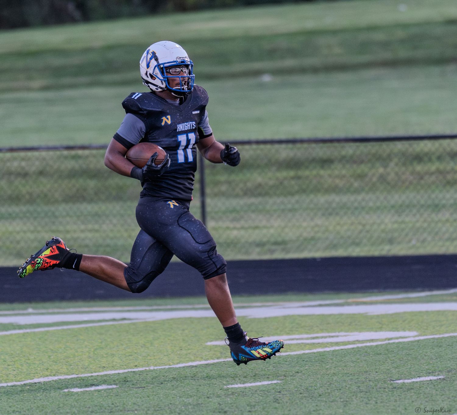 Football player number 11 in black Knights uniform sprints down the sideline.