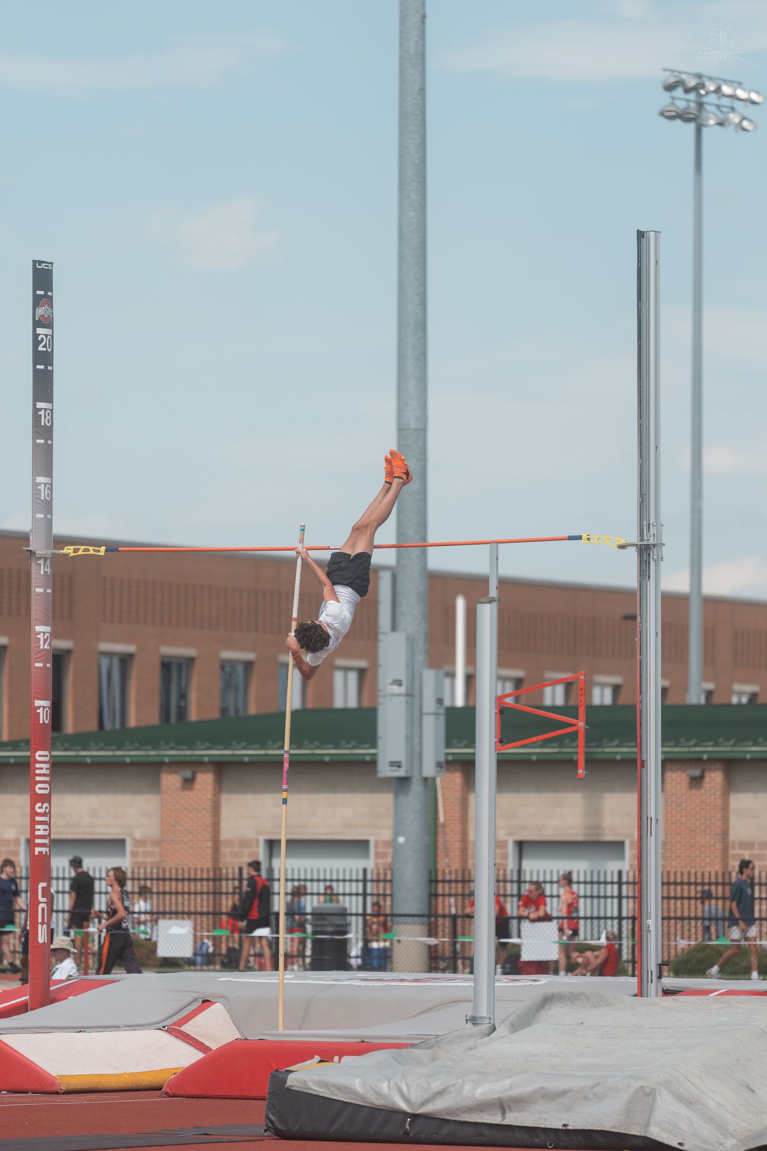 Pole vaulter arches over the crossbar during a high-altitude vault at Ohio State track meet.