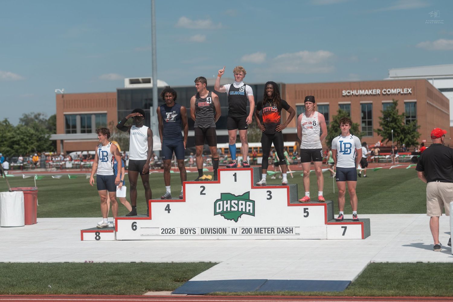 Male track athletes stand on the OHSAA Boys Division IV 200 Meter Dash podium at a sunny championship meet.