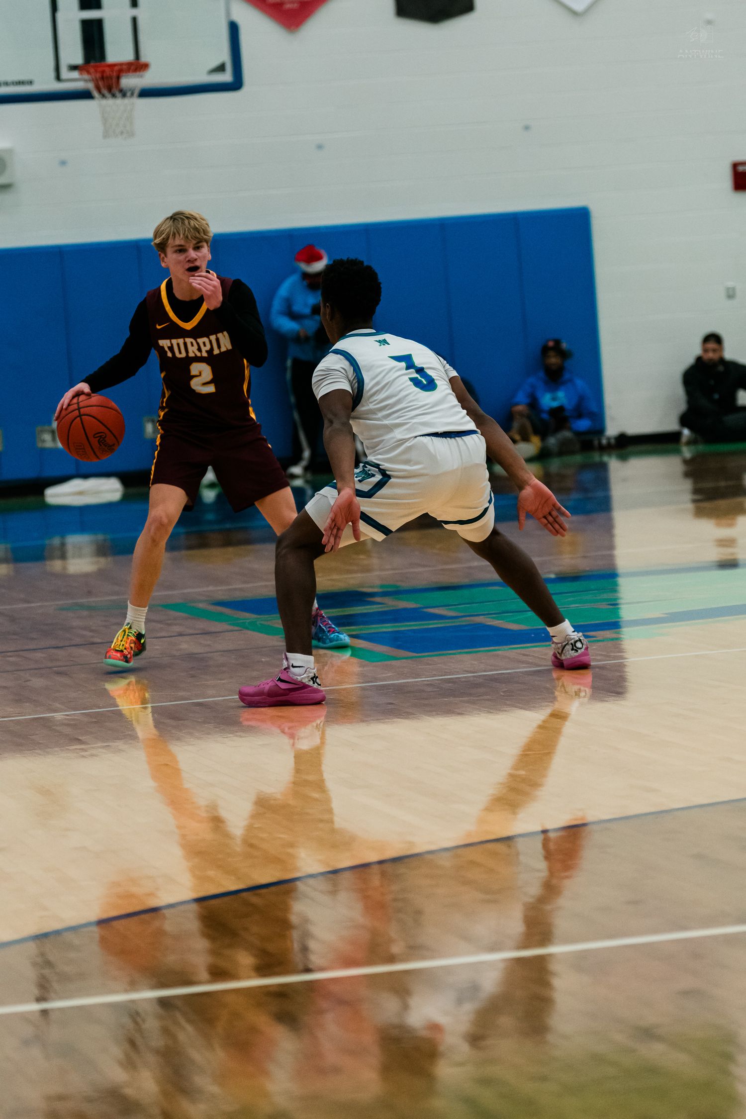 Turpin #2 basketball player dribbles while defended by Warriors player during high school game.