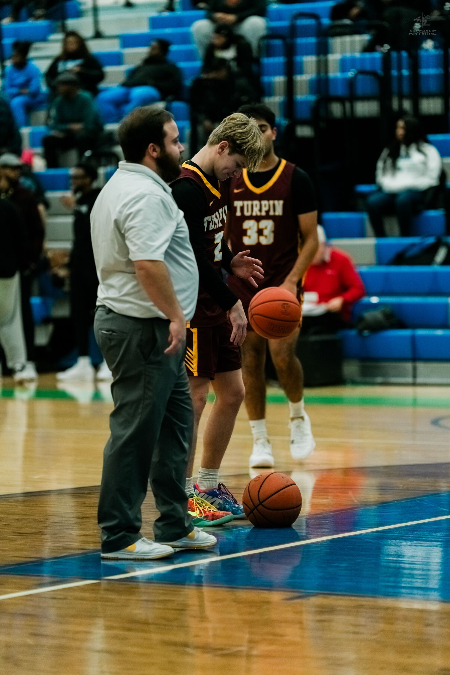 A coach speaks with a Turpin high school basketball player wearing jersey number 33 on the court.