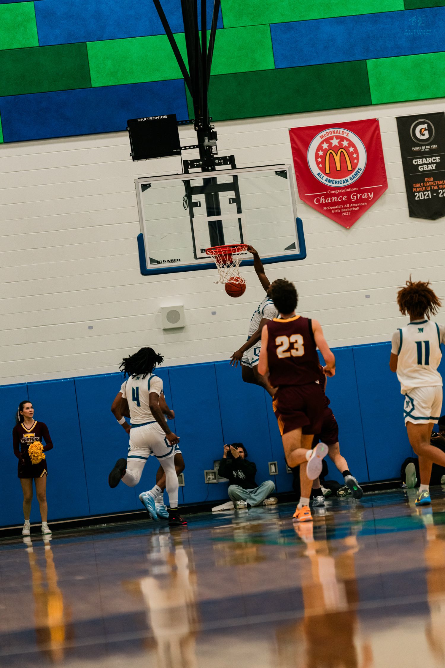 Warriors player dunks basketball over Turpin number 23 defender during high school basketball game.