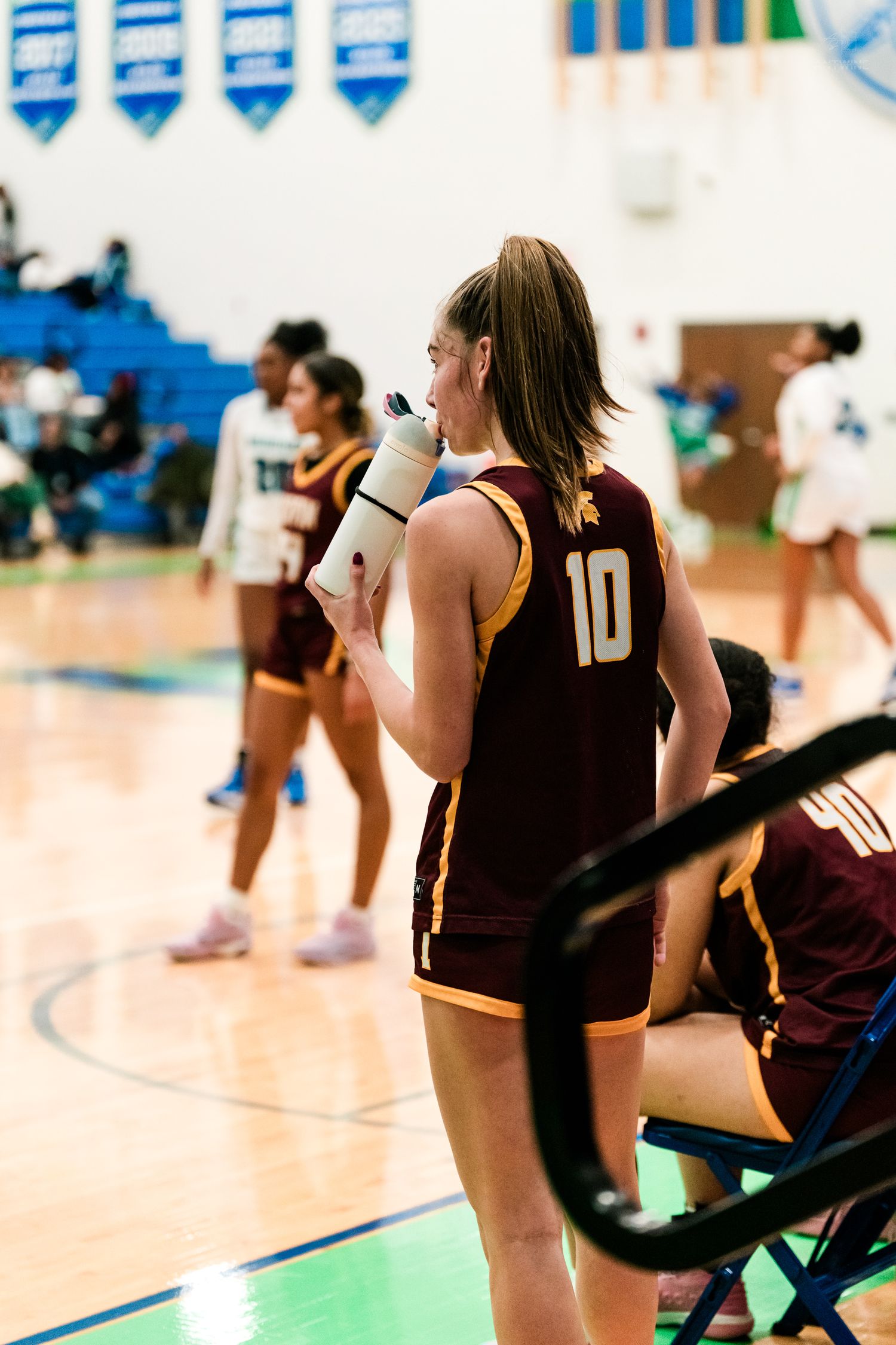 Turpin High School girls basketball player number 10 drinks from a water bottle during a game timeout.